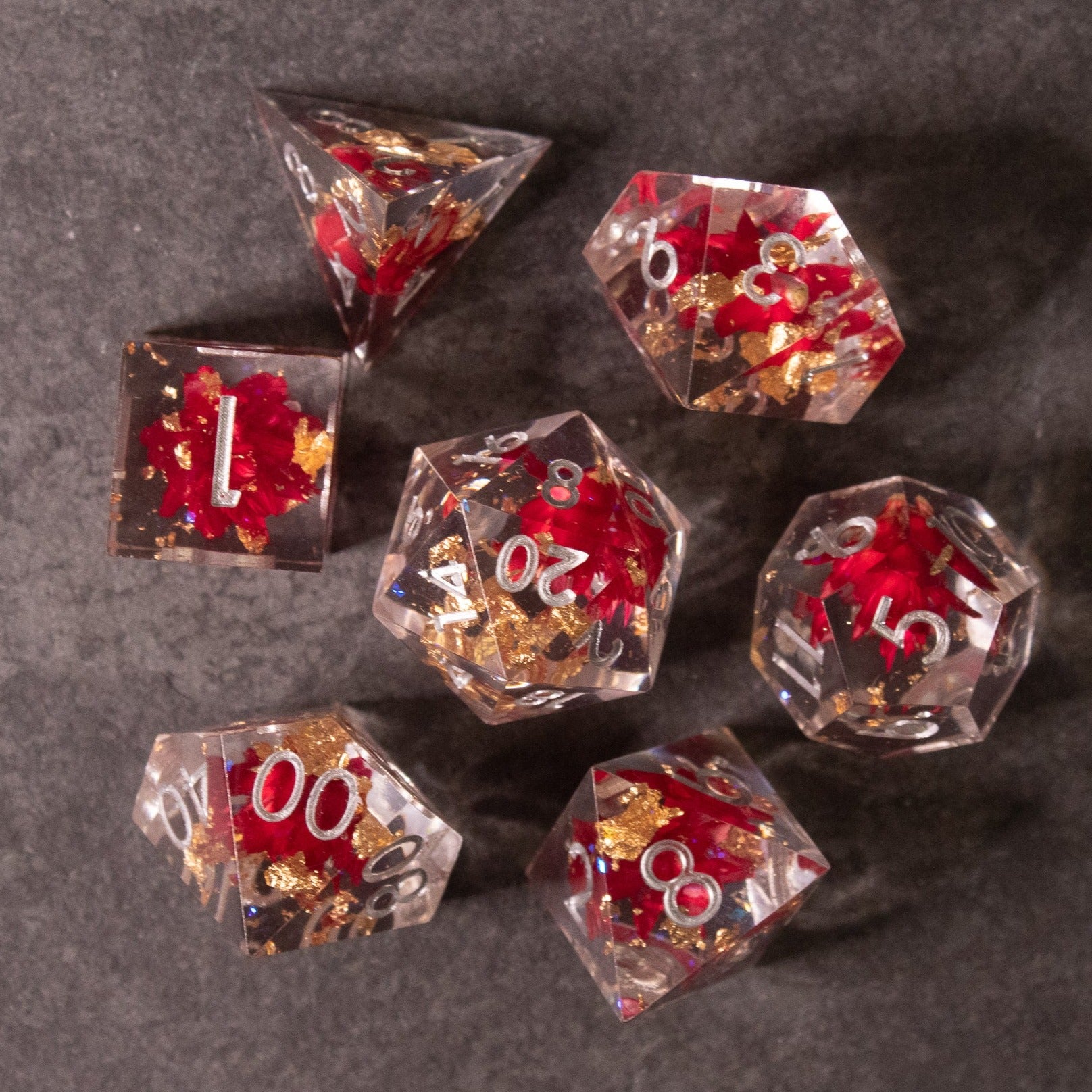 Red Lotus Flower Dice Set - Transparent polyhedral dice set with sharp edges, red lotus flower inclusions, and white numbering.