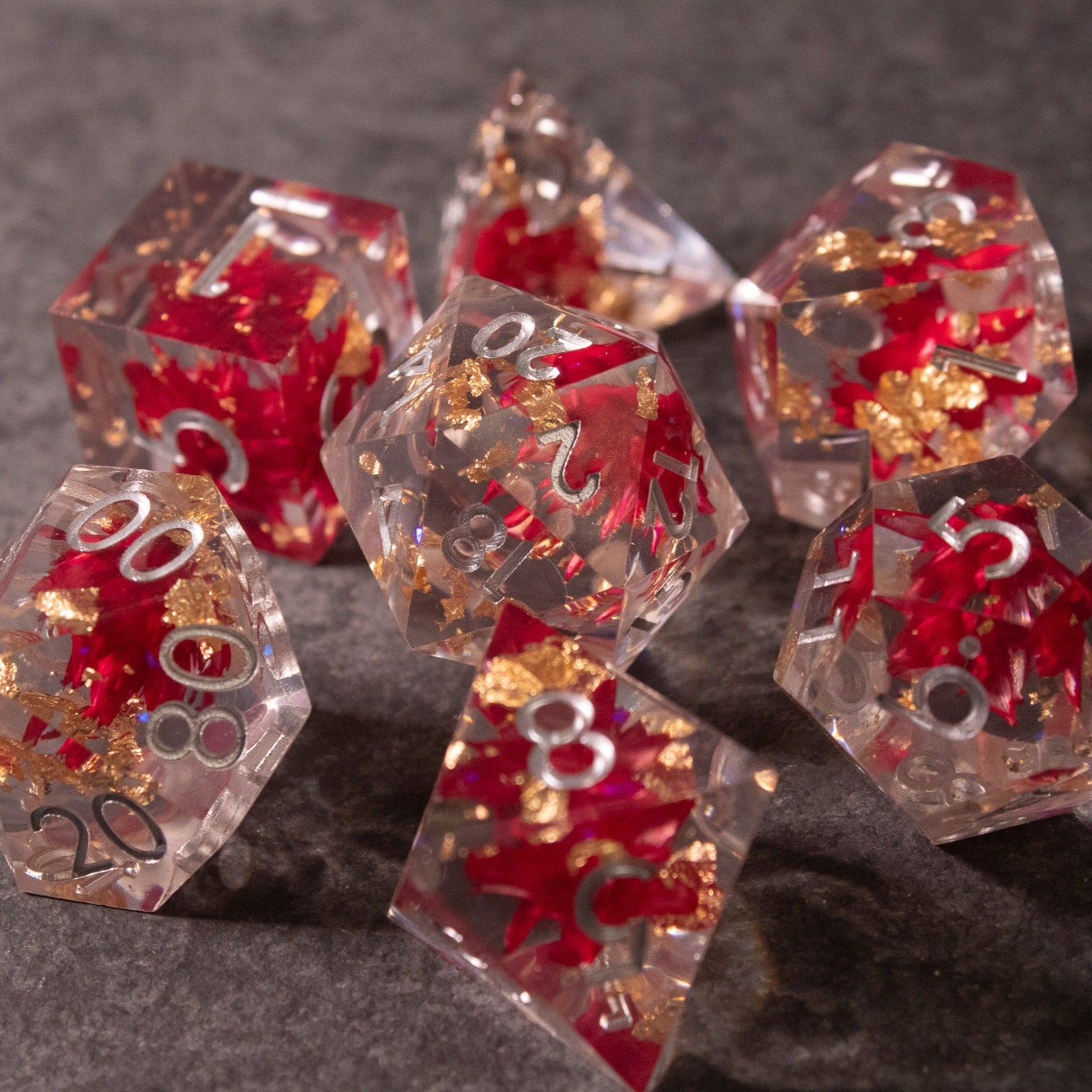 Red Lotus Flower Dice Set - Clear polyhedral dice featuring sharp edges with red lotus flower inclusions and silver numbering.