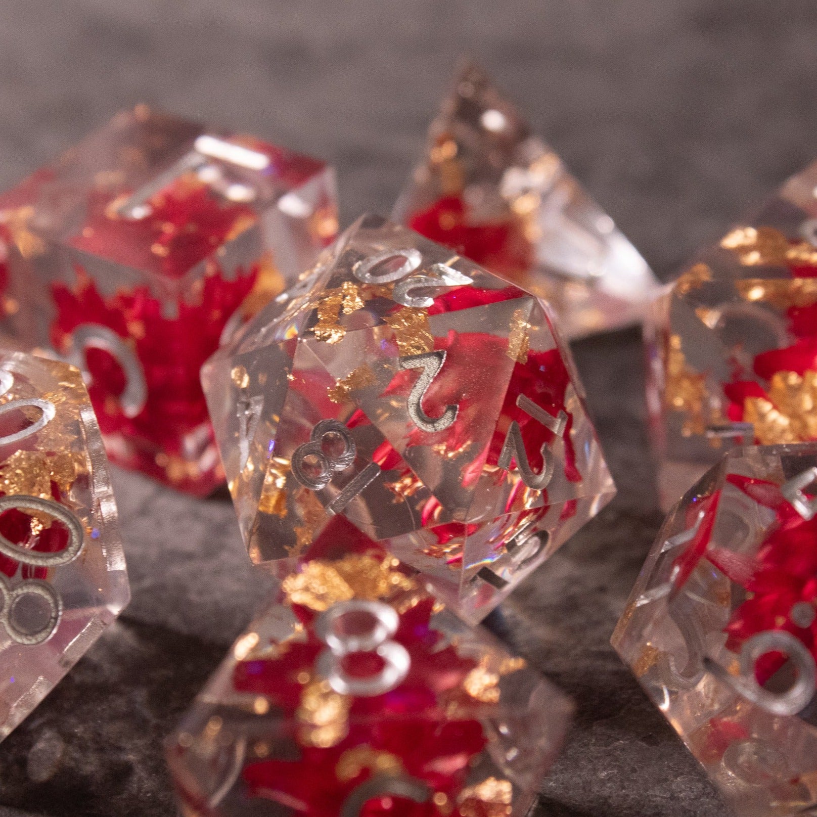 Red Lotus Flower Dice Set - Clear sharp-edged dice with embedded red lotus flower designs and gold flakes, featuring red numbers.