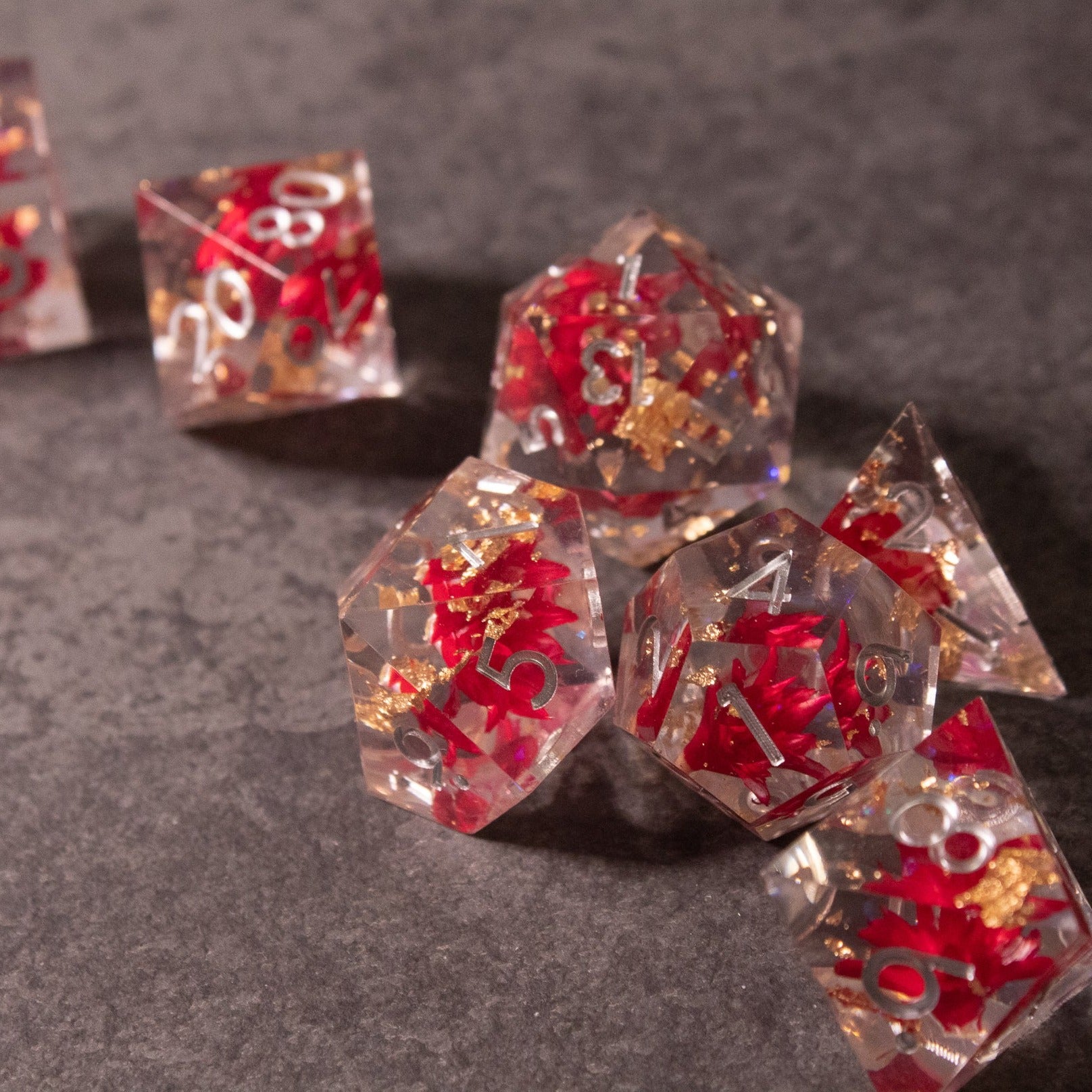Red Lotus Flower Dice Set - Clear polyhedral dice set with embedded red lotus flowers and sharp edges, white numbering.
