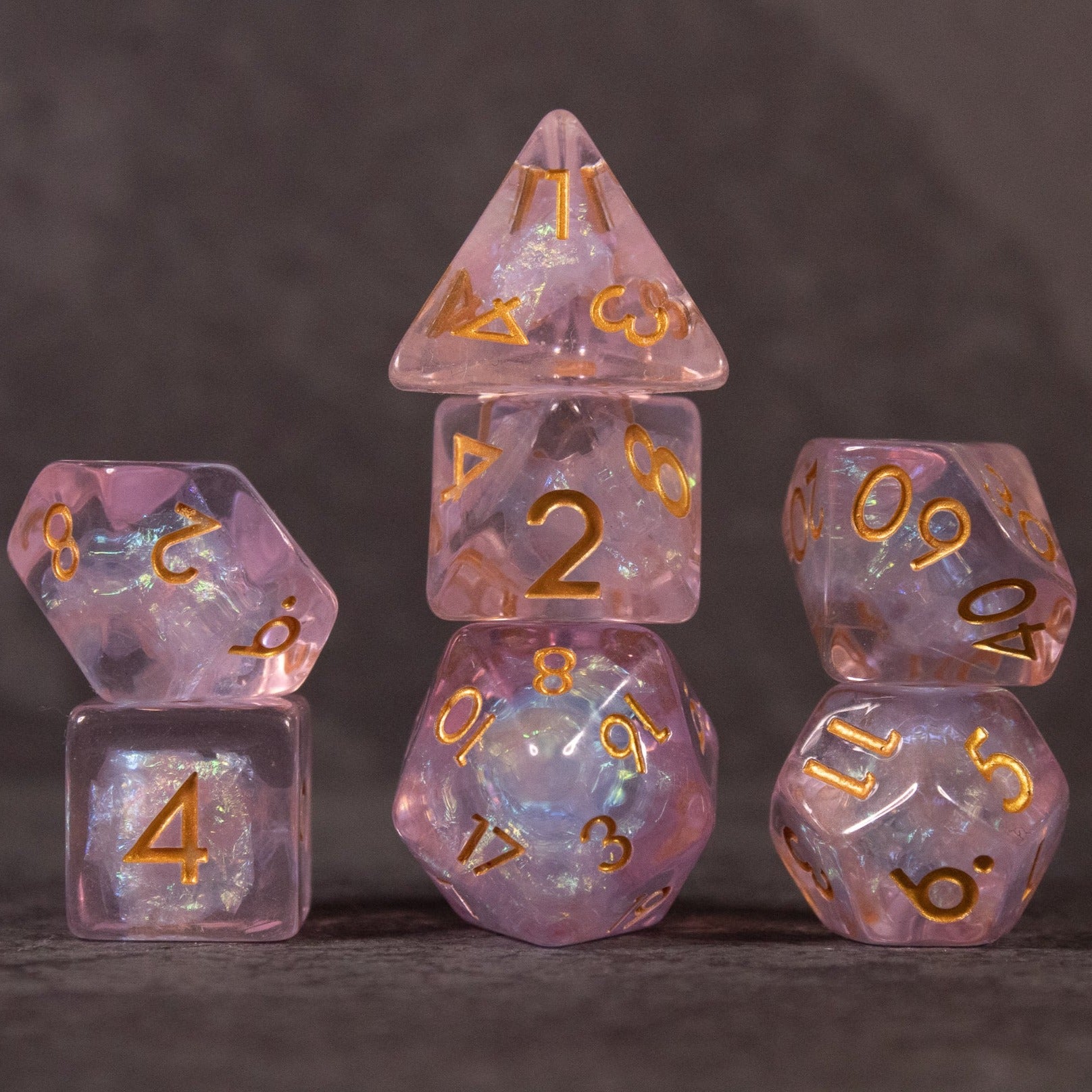 Sakura Dice Set - Set of six iridescent pink polyhedral dice with gold numbers, featuring translucent and marbled textures.