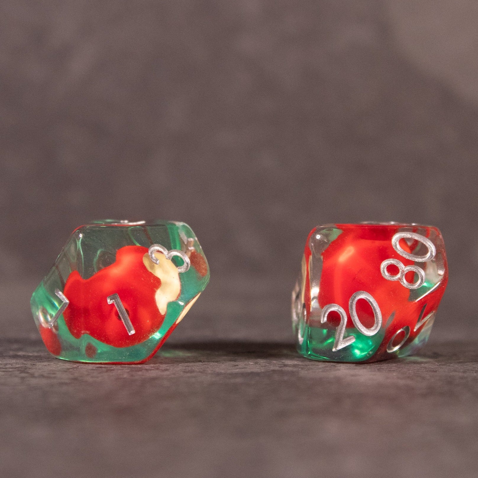 Apple Bite Dice Set - Two transparent dice with green and red swirls containing small red apple shapes and white numbers on their faces.