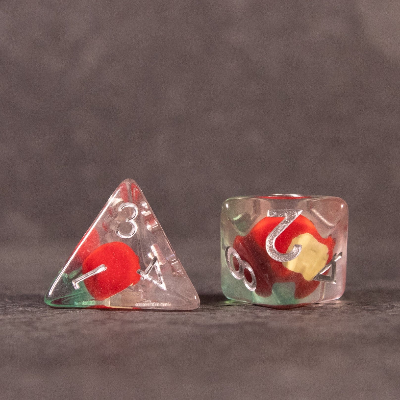 Apple Bite Dice Set - Clear acrylic dice with embedded red apple shapes, one four-sided and one six-sided.