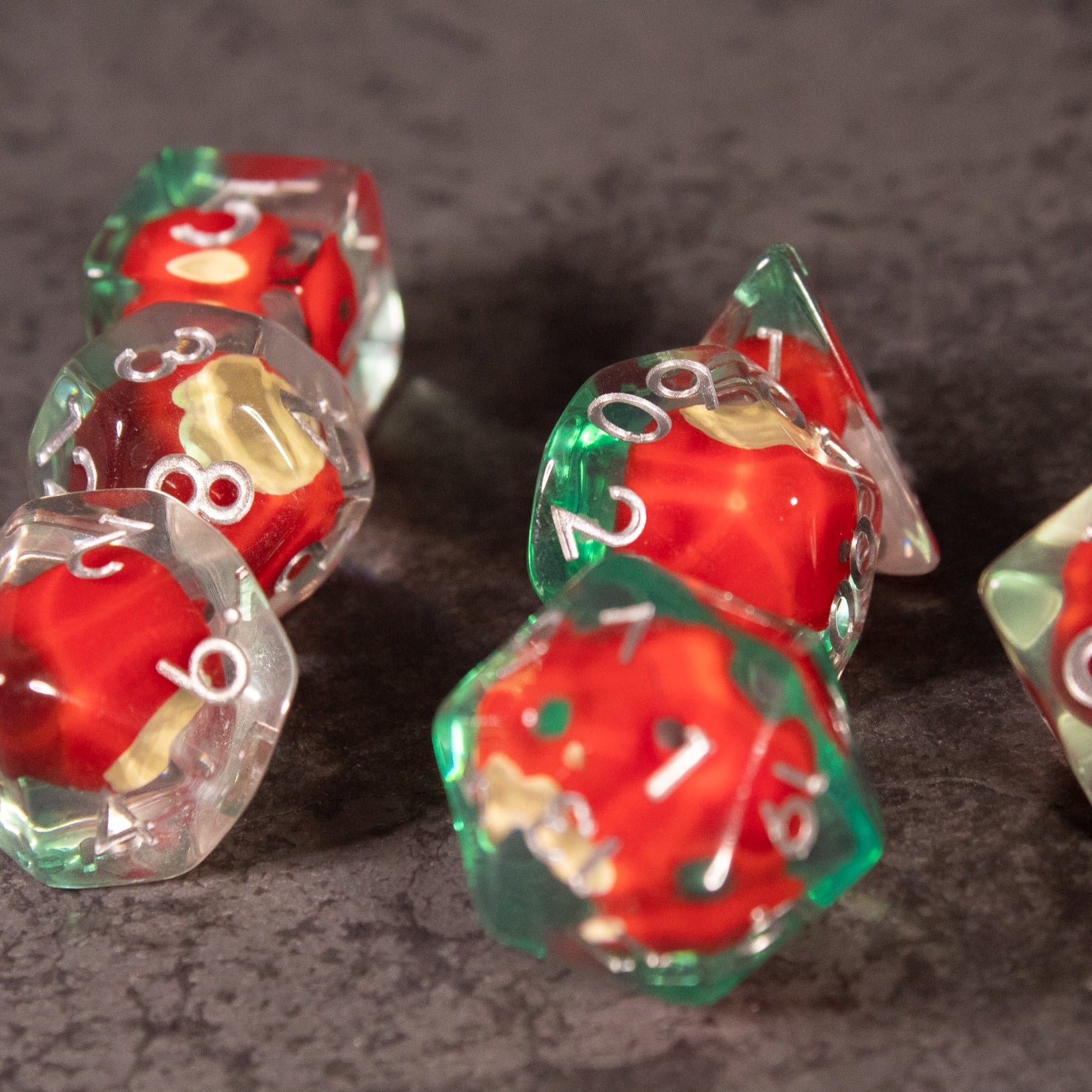 Apple Bite Dice Set - Transparent polyhedral dice with red apple core designs and green leaf details inside.