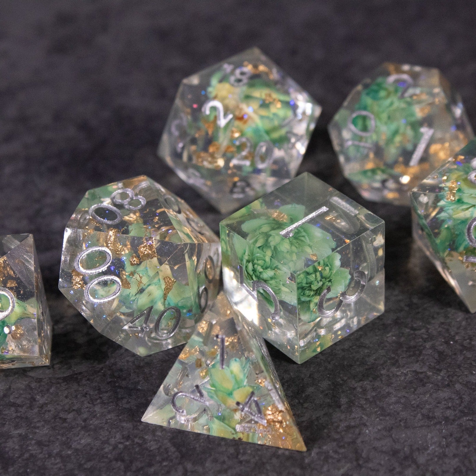 Teal Lotus Flower Dice Set - Transparent sharp-edged polyhedral dice set with green lotus flower and gold foil inclusions.