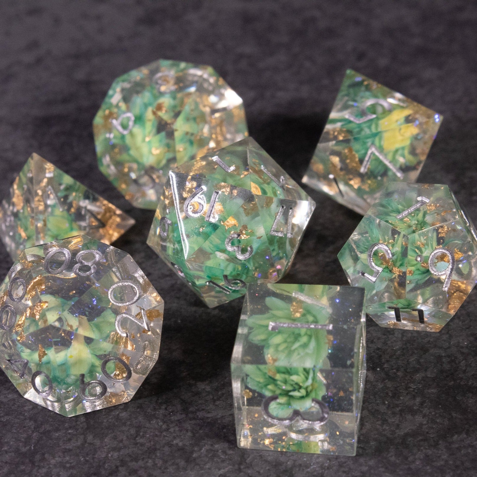 Teal Lotus Flower Dice Set - Teal lotus flower sharp edge dice set with translucent resin and gold flecks on black background.