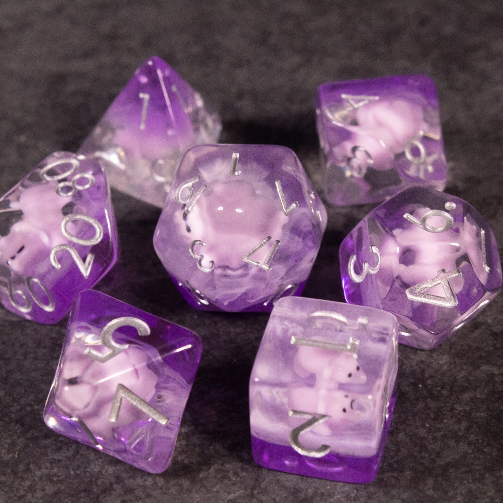 Pink Triceratops Dice Set - Purple and pink translucent dinosaur-themed polyhedral dice set with white numbers.