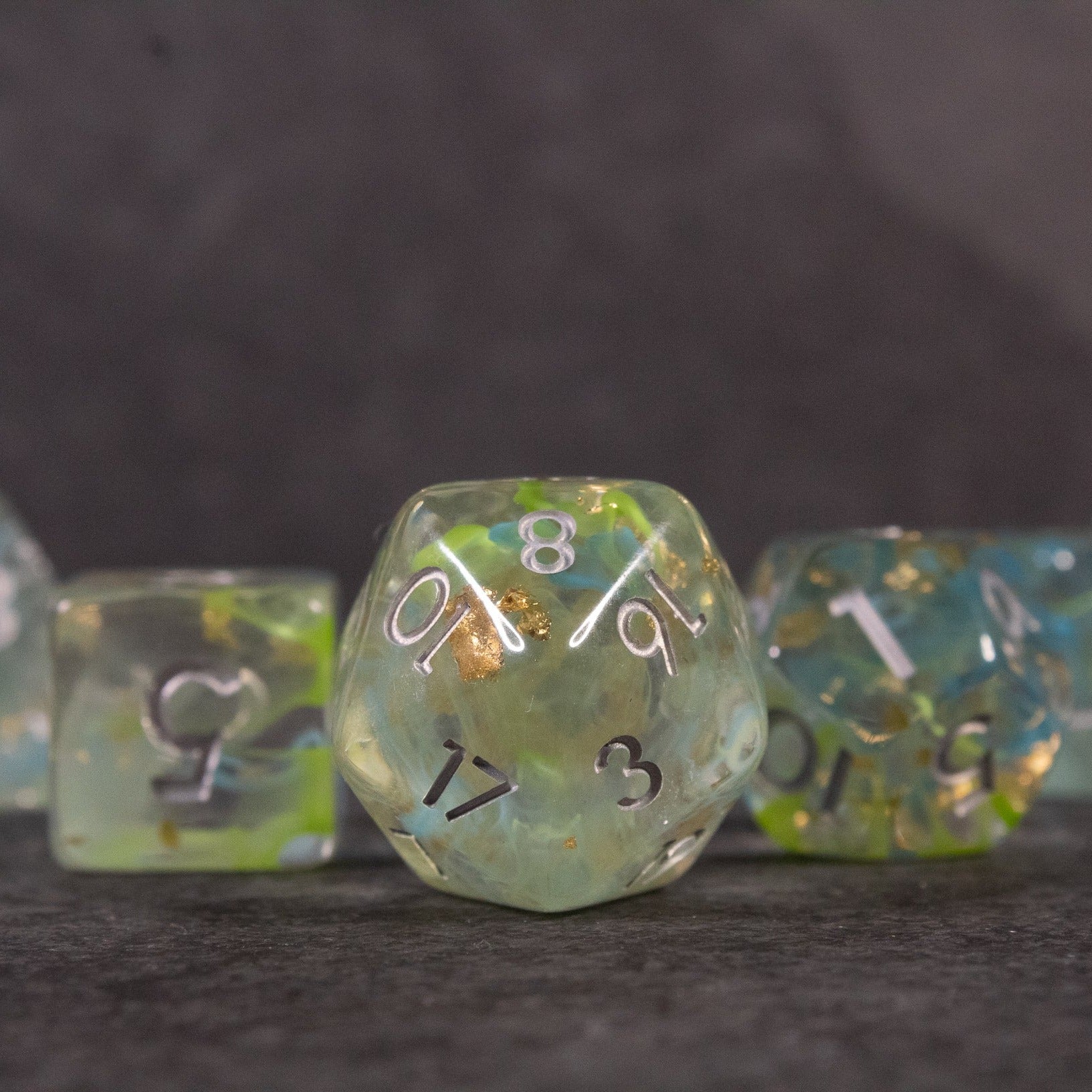Blue, Green, and Gold Swirl Dice Set - Set of blue, green, and gold swirl polyhedral dice with white and black numbers.