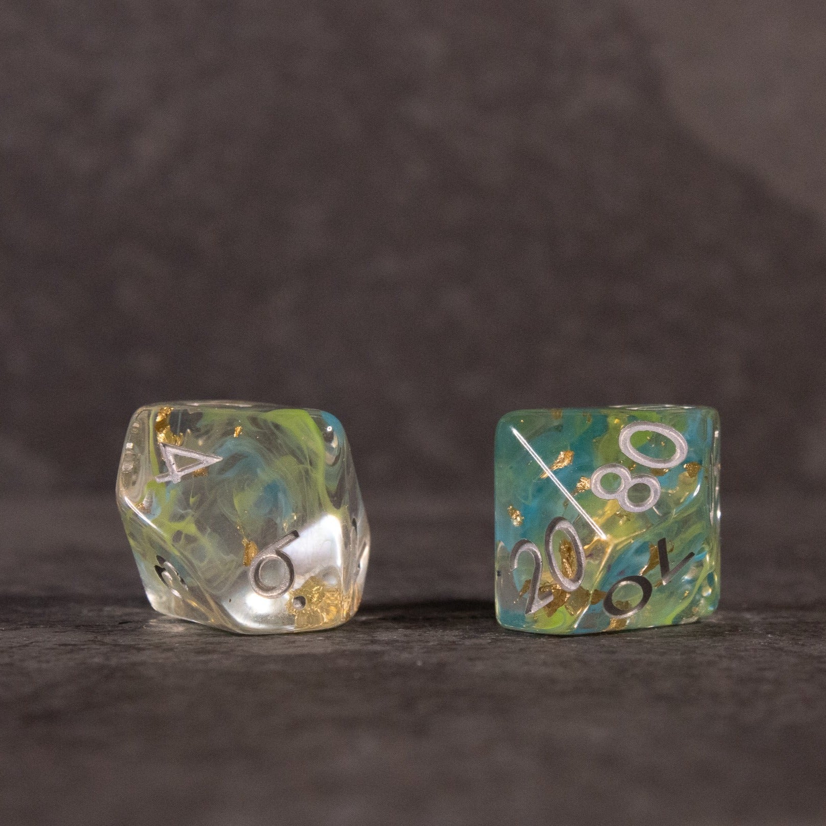 Blue, Green, and Gold Swirl Dice Set - Translucent blue and green swirl d20 and d10 dice with gold numbering on dark background.