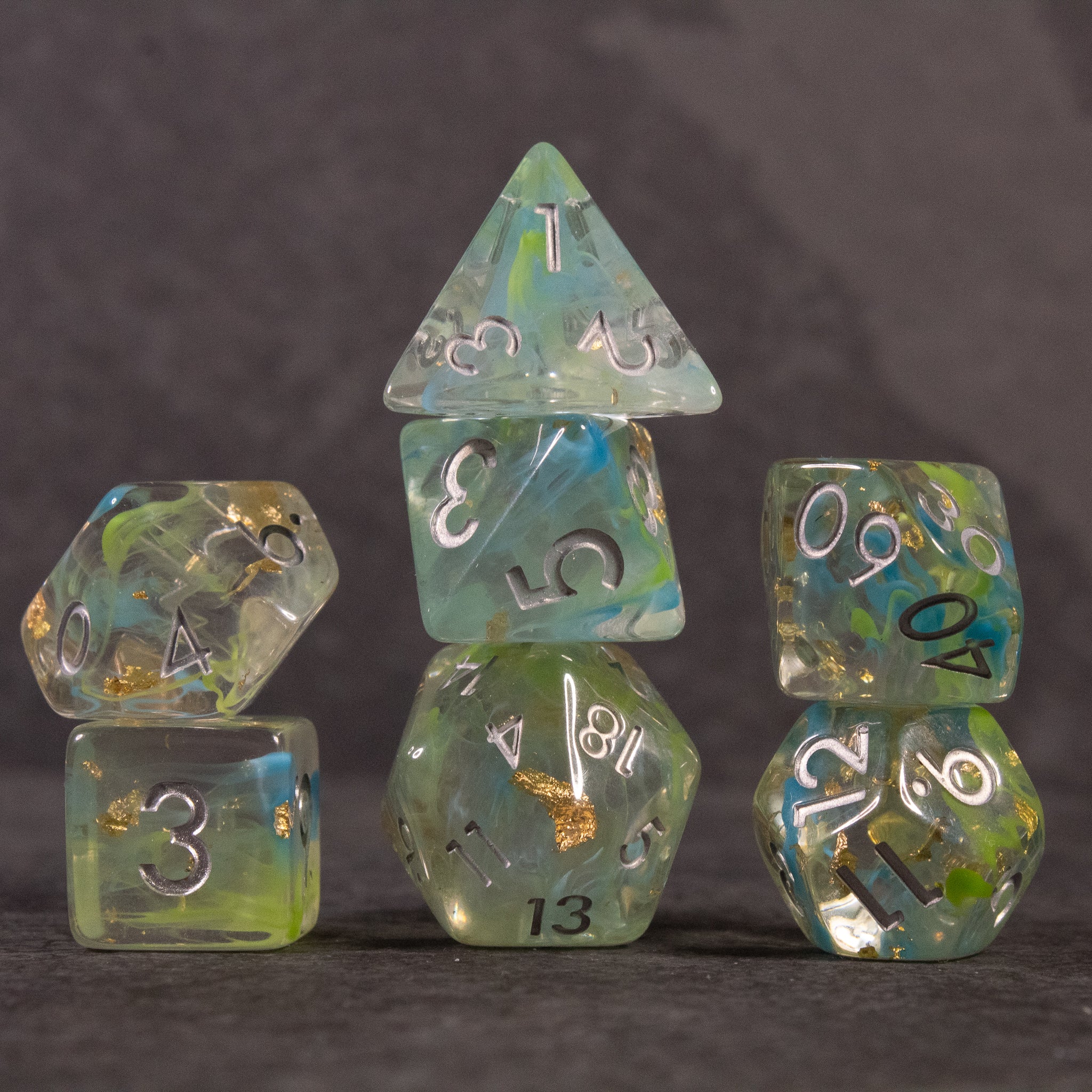 Blue, Green, and Gold Swirl Dice Set - Translucent blue, green, and gold swirl polyhedral dice set with white numbers.