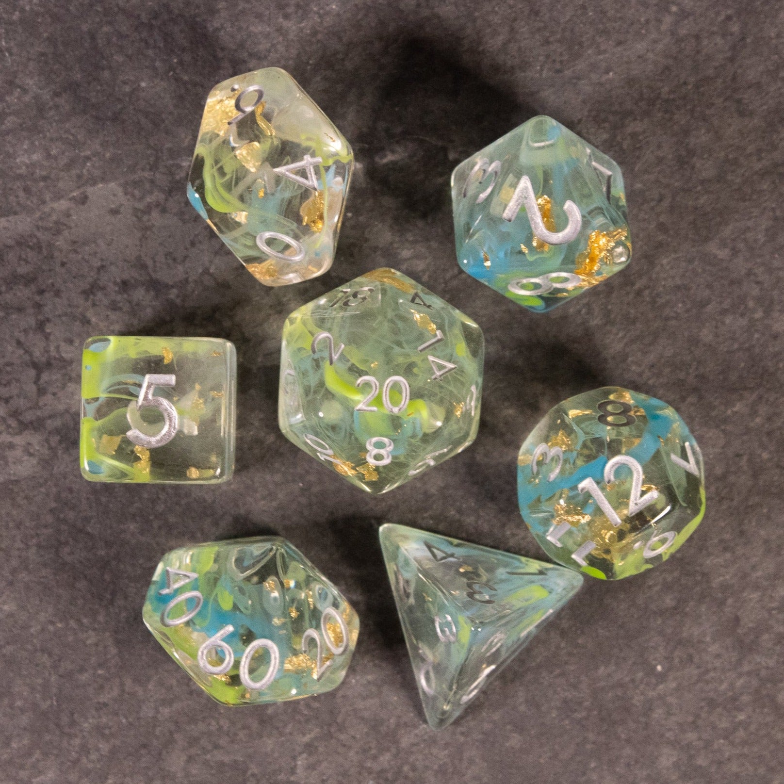 Blue, Green, and Gold Swirl Dice Set - Transparent polyhedral dice set with blue, green, and gold swirls and white numbers.