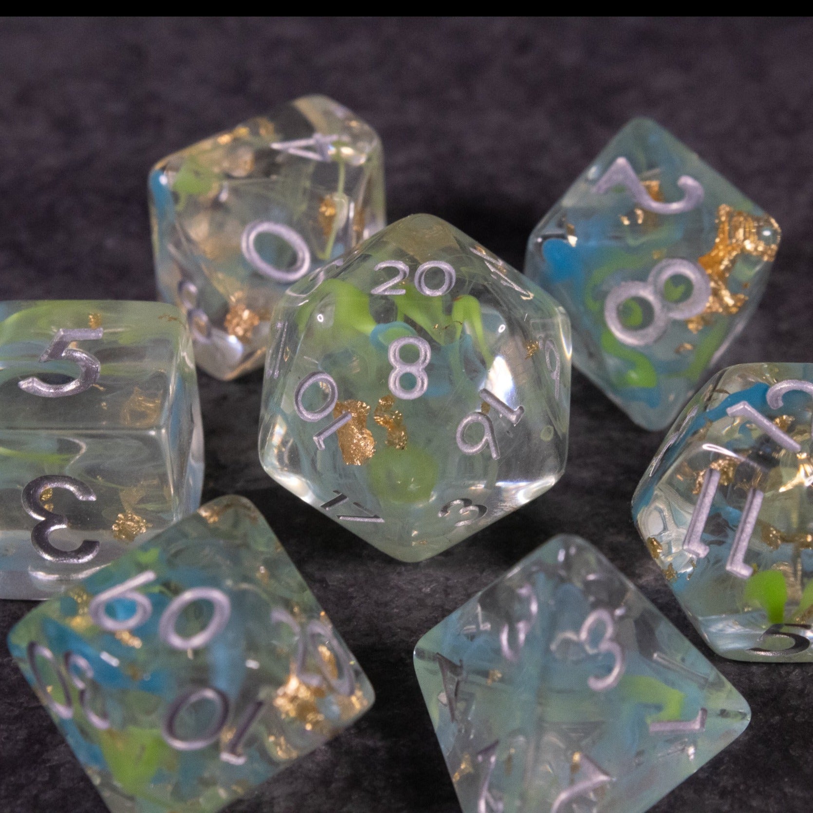 Blue, Green, and Gold Swirl Dice Set - Transparent dice set with blue, green, and gold swirls and white numbering, featuring a 20-sided die in center.