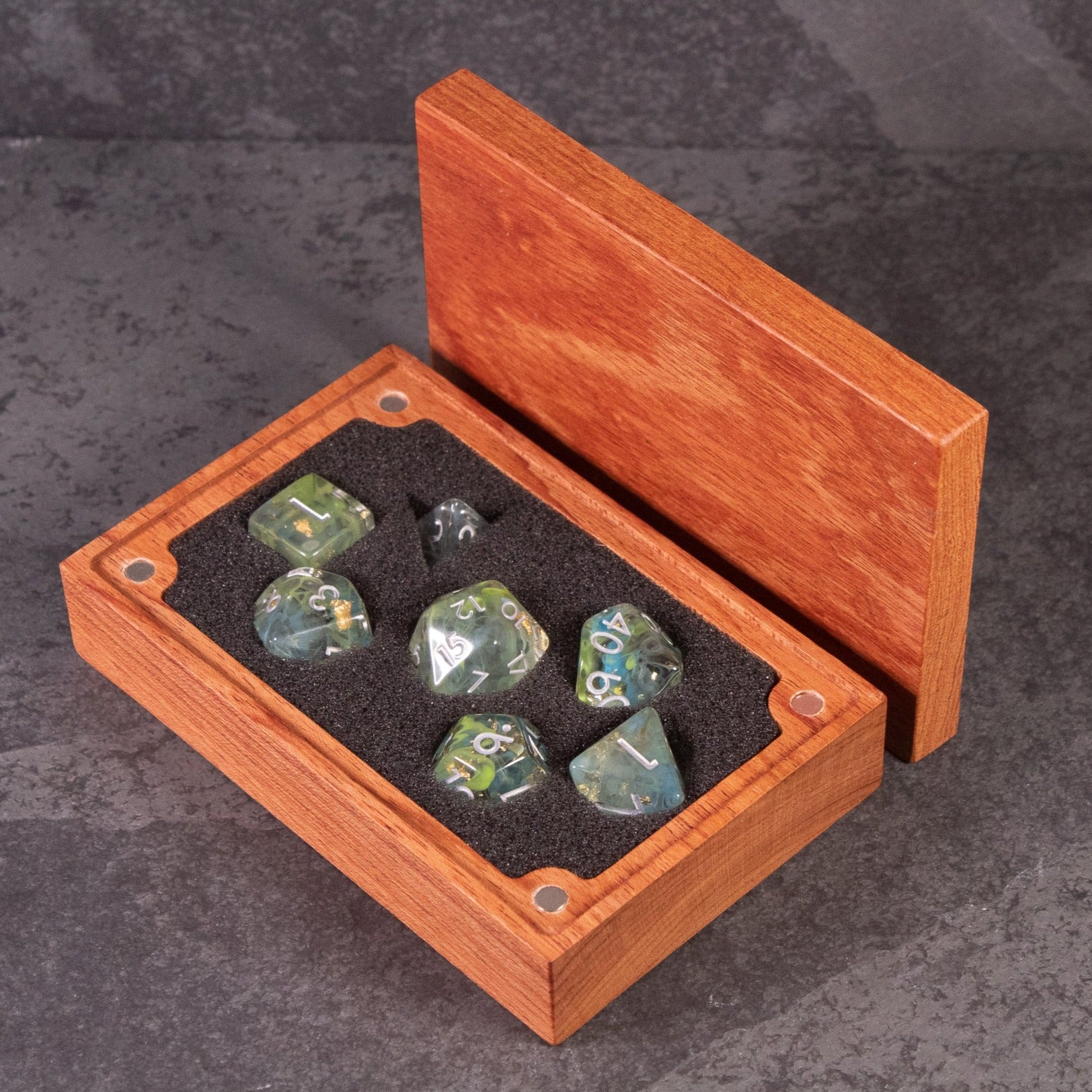 Blue, Green, and Gold Swirl Dice Set - Set of seven polyhedral dice with swirling blue, green, and gold colors, displayed in a wooden box with black foam lining.