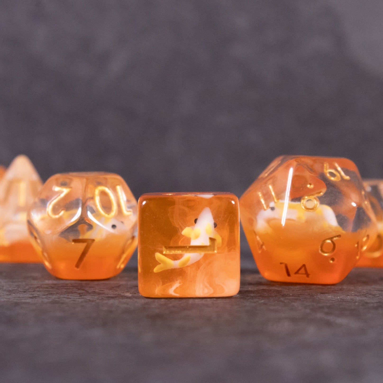 Orange Koi Fish Dice Set - Transparent orange dice set with miniature koi fish floating inside each die, including d20 and d8 shapes.
