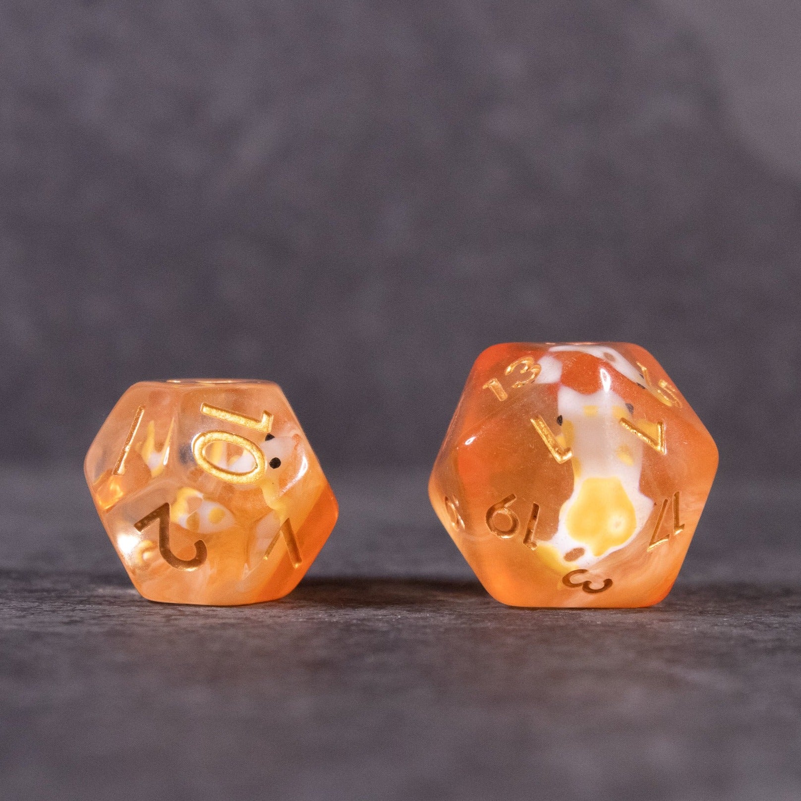 Orange Koi Fish Dice Set - Two translucent orange d20 dice with gold numbers and embedded koi fish designs on gray background.
