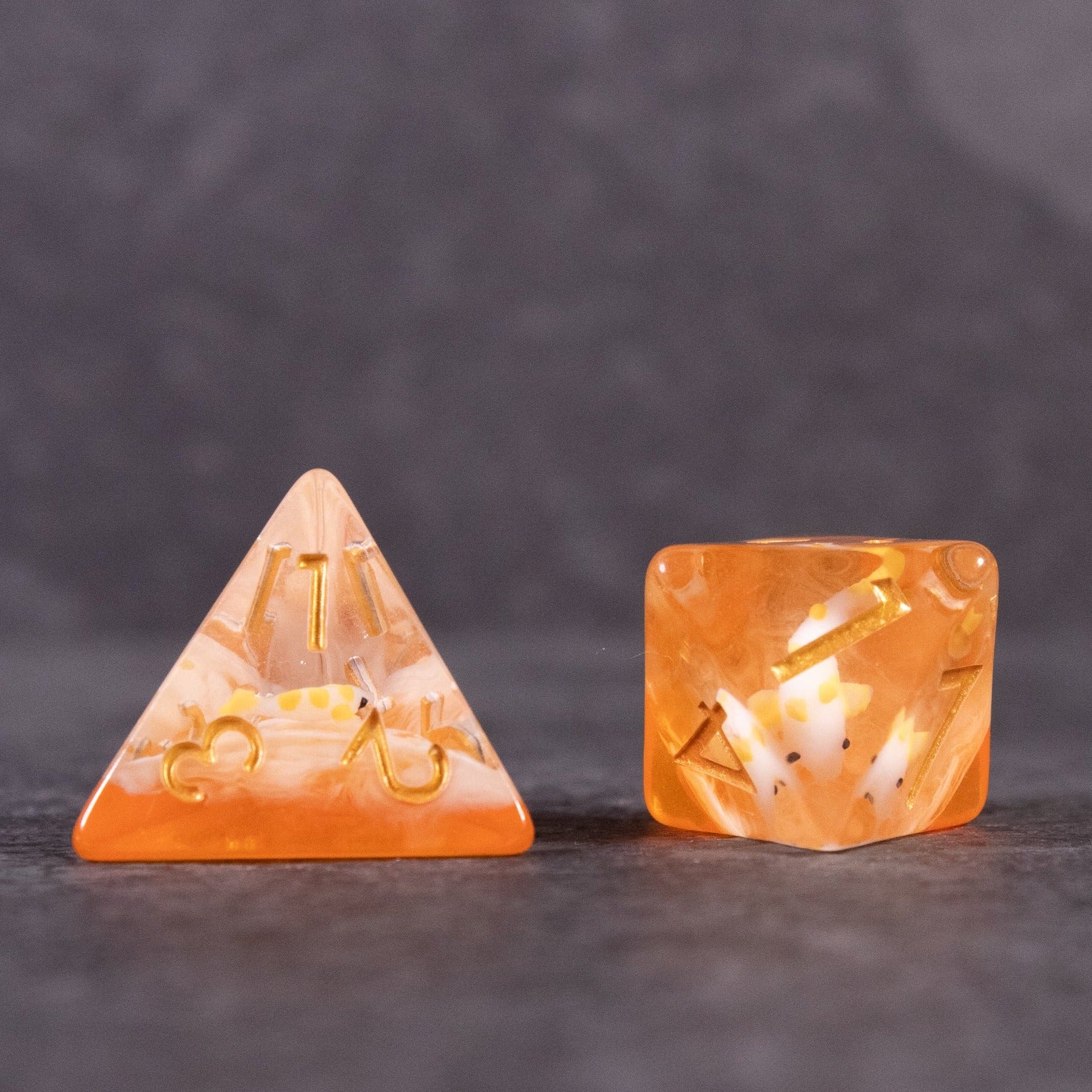 Orange Koi Fish Dice Set - Set of two translucent orange dice with gold numbers, one four-sided and one six-sided, featuring koi fish inclusions.