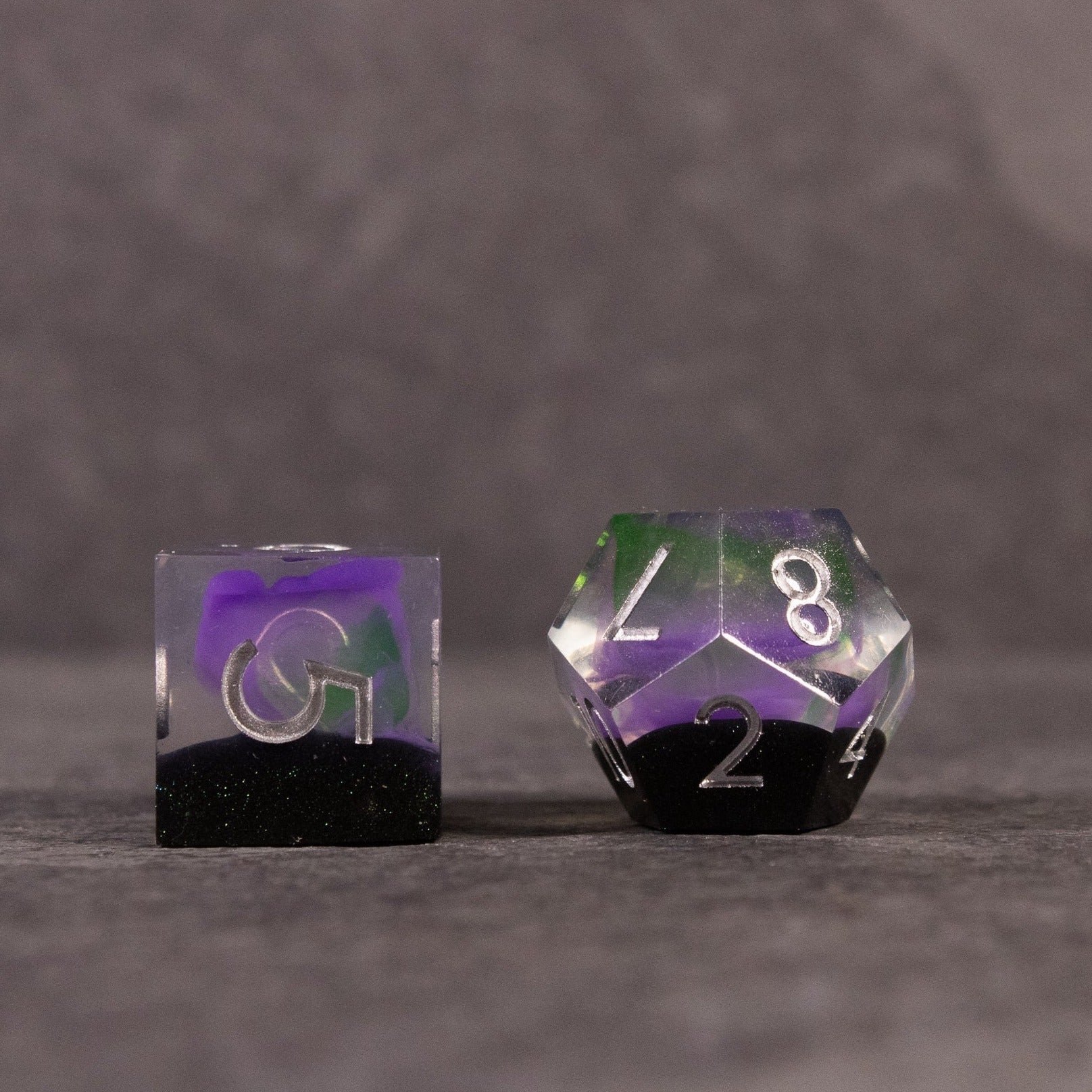 Witch's Brew Dice Set - Set of sharp-edged dice with green and purple swirls encased in clear resin, black bottoms, white numbers.