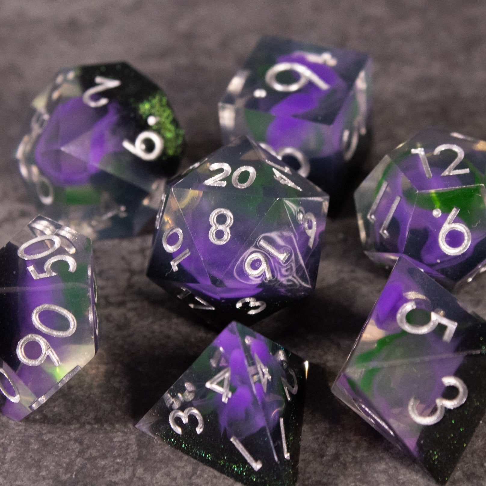 Witch's Brew Dice Set - Seven sharp-edged polyhedral dice with swirling purple and green colors and white numbering.