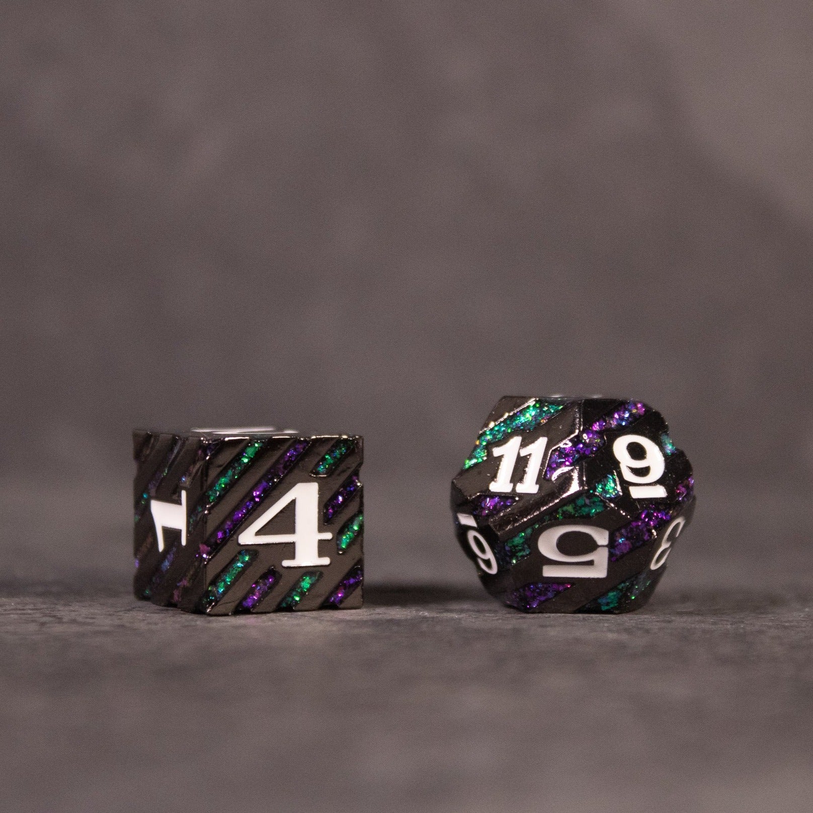 Arcane Leyline Dice Set - Purple & Green - Black metal dice with shimmering purple and green streaks, white numbers, including a 4-sided ring and a 12-sided die.