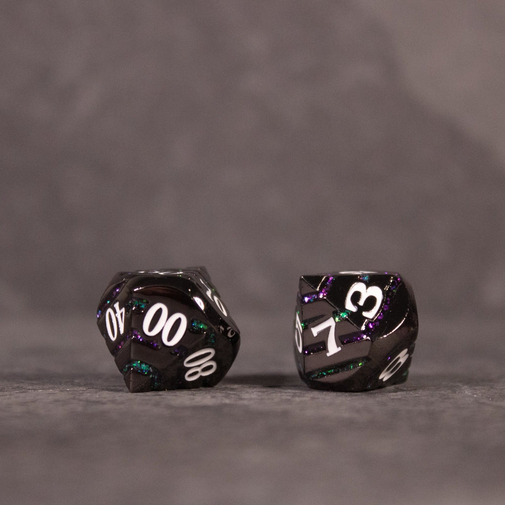 Arcane Leyline Dice Set - Purple & Green - Black metal dice with purple and green swirls, white numbering, showing a d10 and percentile die.