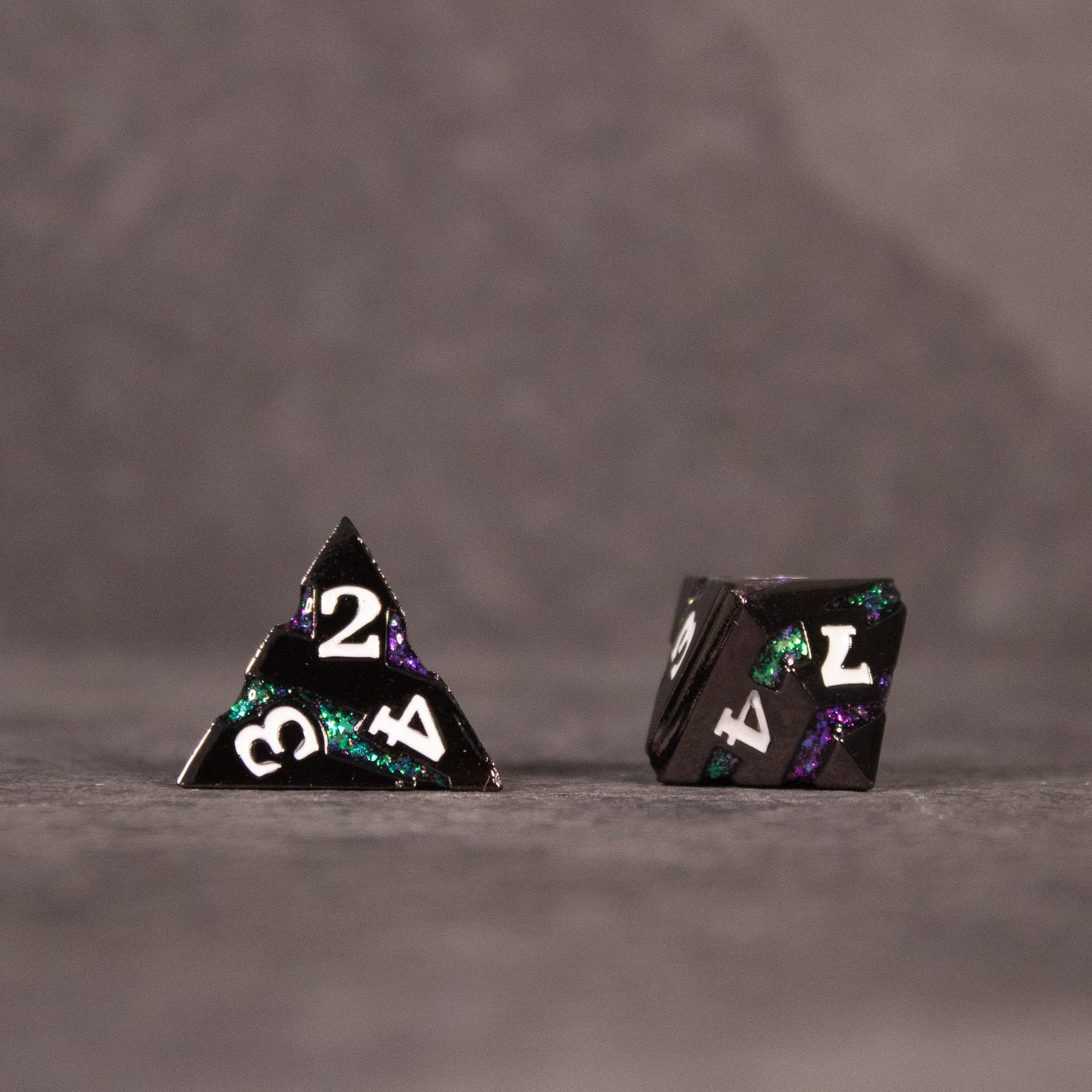 Arcane Leyline Dice Set - Purple & Green - Set of two metal dice with a dark base, featuring glowing purple and green swirls and white numbers, including a four-sided.