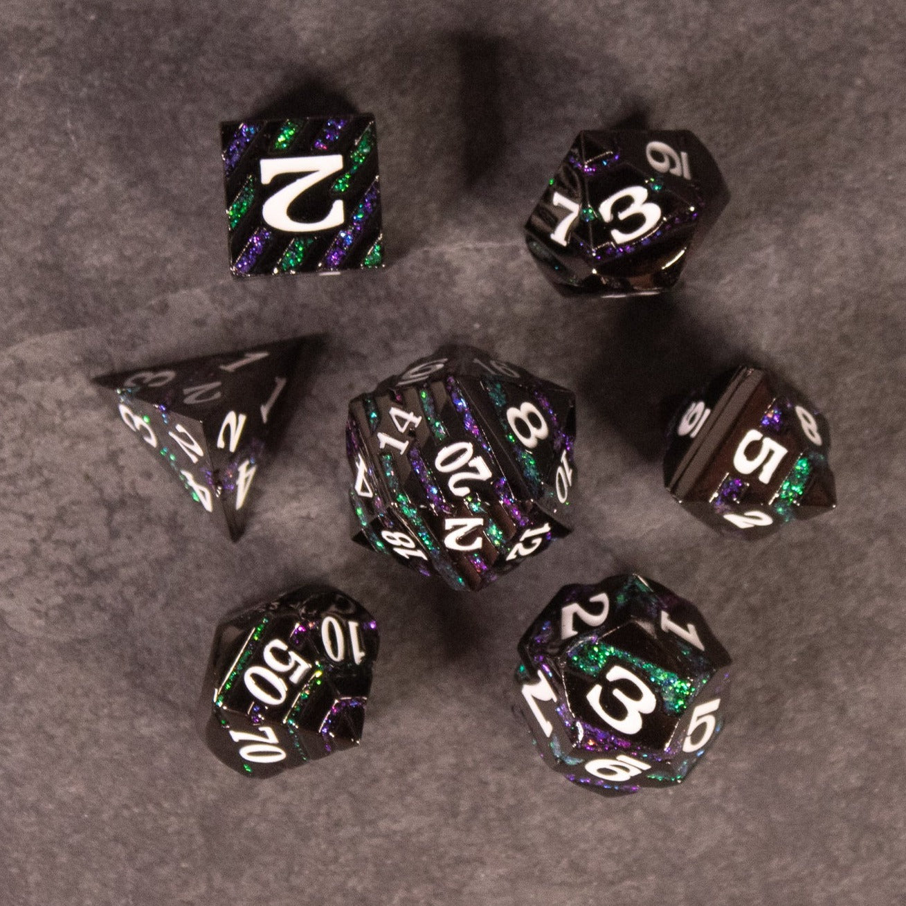 Arcane Leyline Dice Set - Purple & Green - Seven black metal polyhedral dice with iridescent purple and green swirls and white numbering, designed for tabletop gaming.