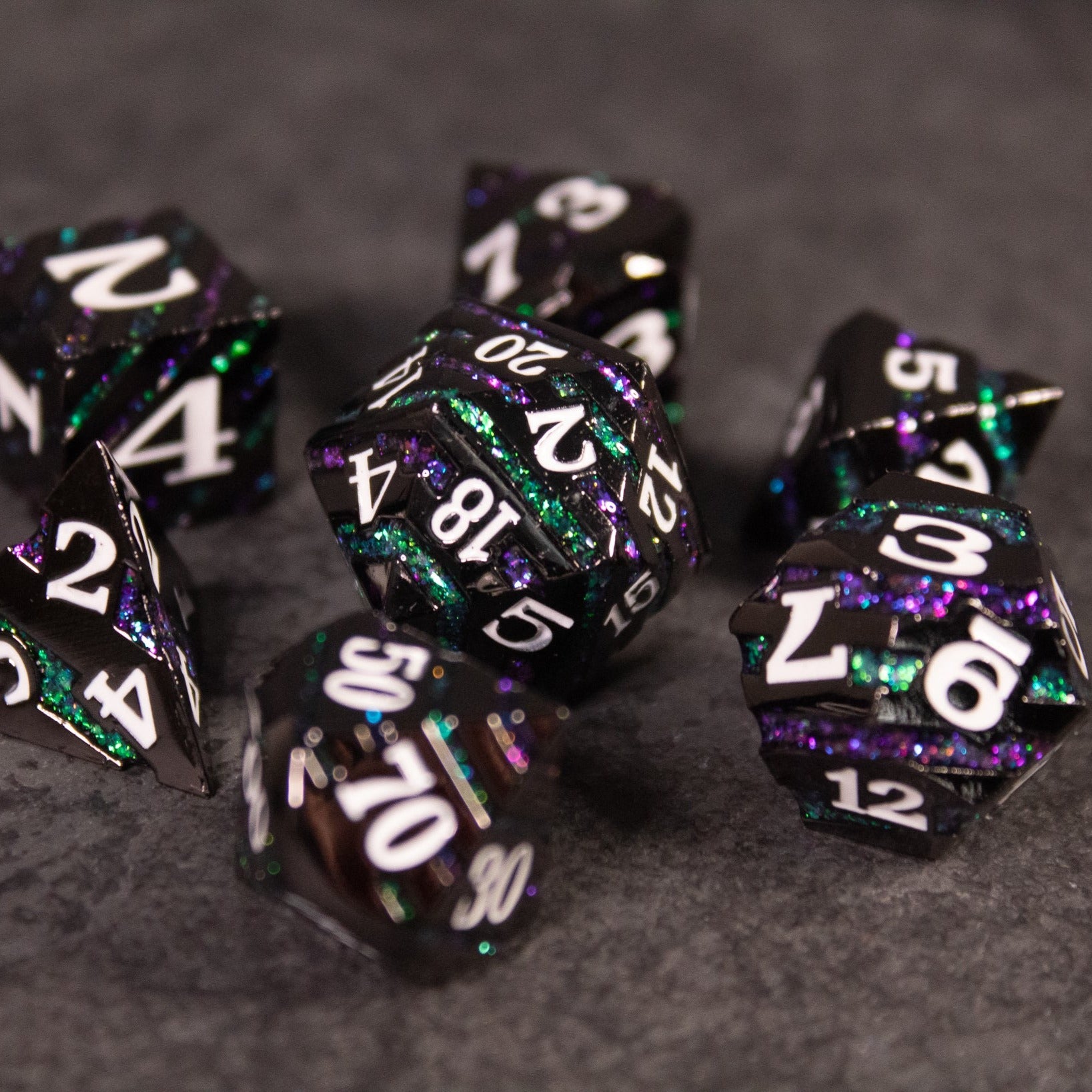 Arcane Leyline Dice Set - Purple & Green - Set of metallic purple and green polyhedral dice with white numbering on dark textured background.