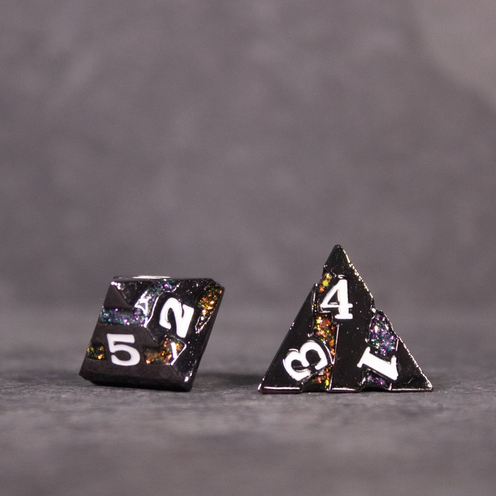 Arcane Leyline Dice Set - Orange & Pink - Two black metal polyhedral dice with orange and pink speckled accents, glowing numbers, and a subtle shimmer.