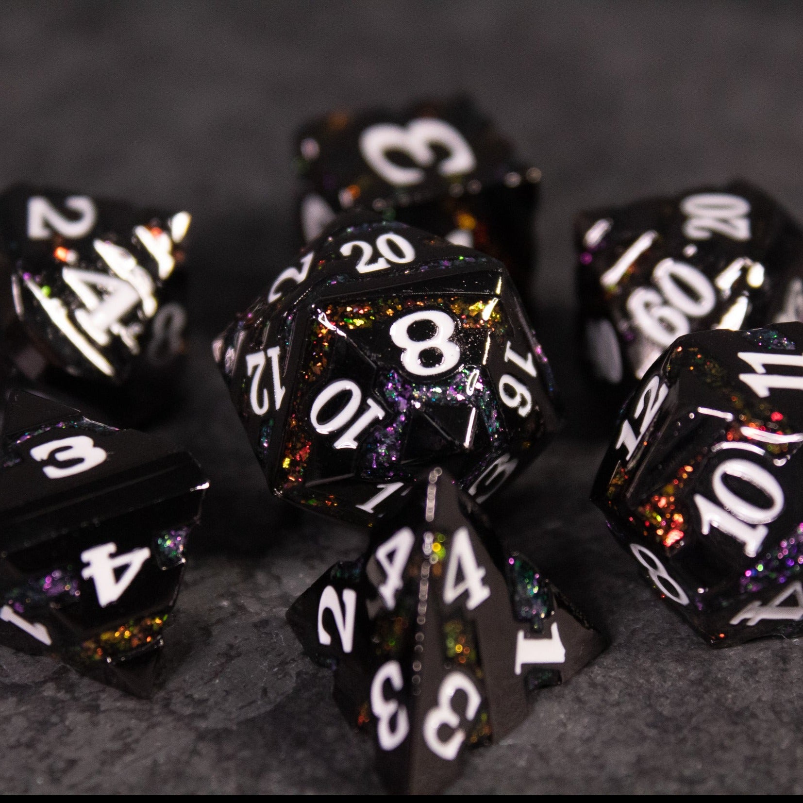 Arcane Leyline Dice Set - Orange & Pink - Set of black metal polyhedral dice with orange and pink shimmering flecks and white numbering.