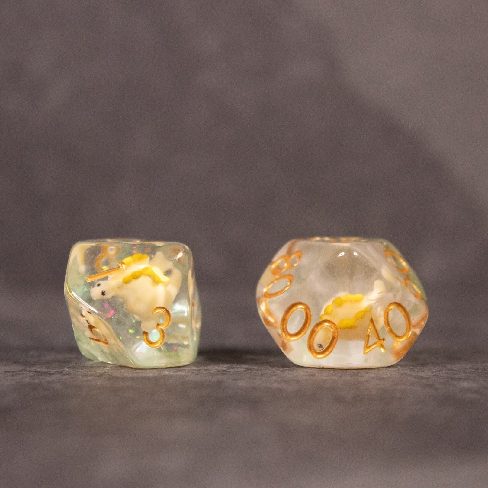 Yellow Stegosaurus Dice Set - Yellow stegosaurus figurines encased in transparent dice with gold numbers on gray surface.
