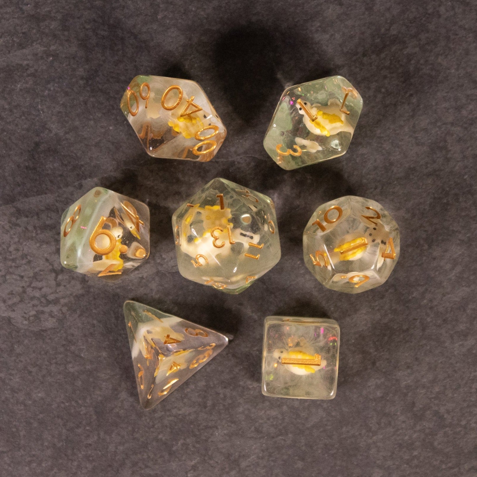 Yellow Stegosaurus Dice Set - Transparent polyhedral dice with yellow numbers and small yellow stegosaurus figures inside on a dark background.