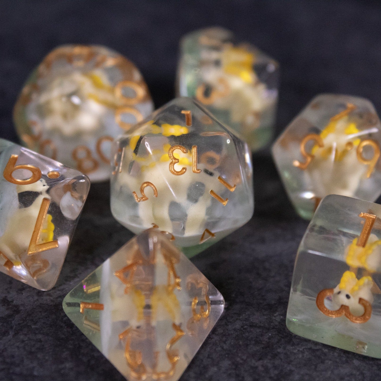 Yellow Stegosaurus Dice Set - Clear yellow polyhedral dice with embedded miniature stegosaurus figures and gold numbers for tabletop gaming.