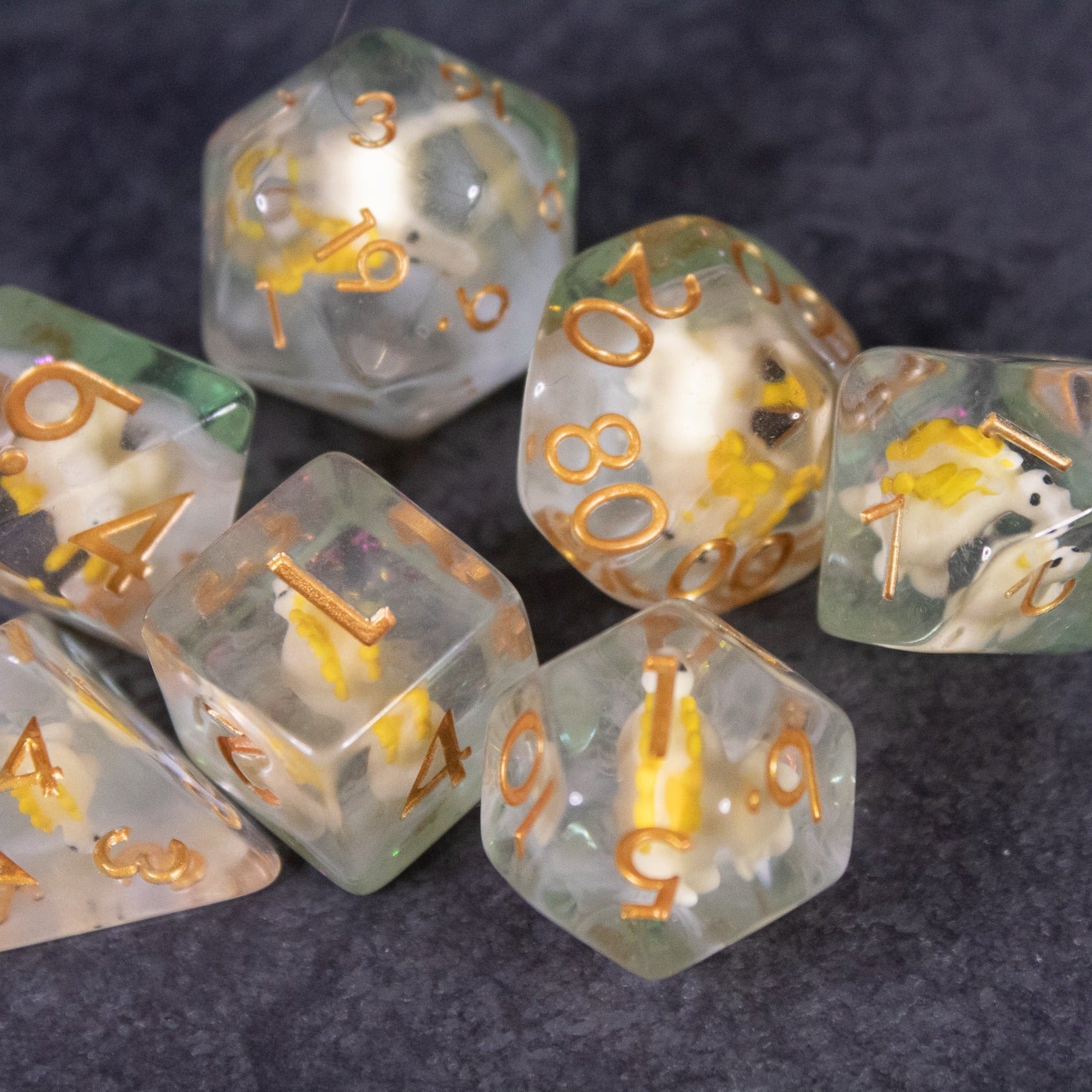 Yellow Stegosaurus Dice Set - Translucent yellow polyhedral dice set with gold numbers and embedded miniature stegosaurus figures.