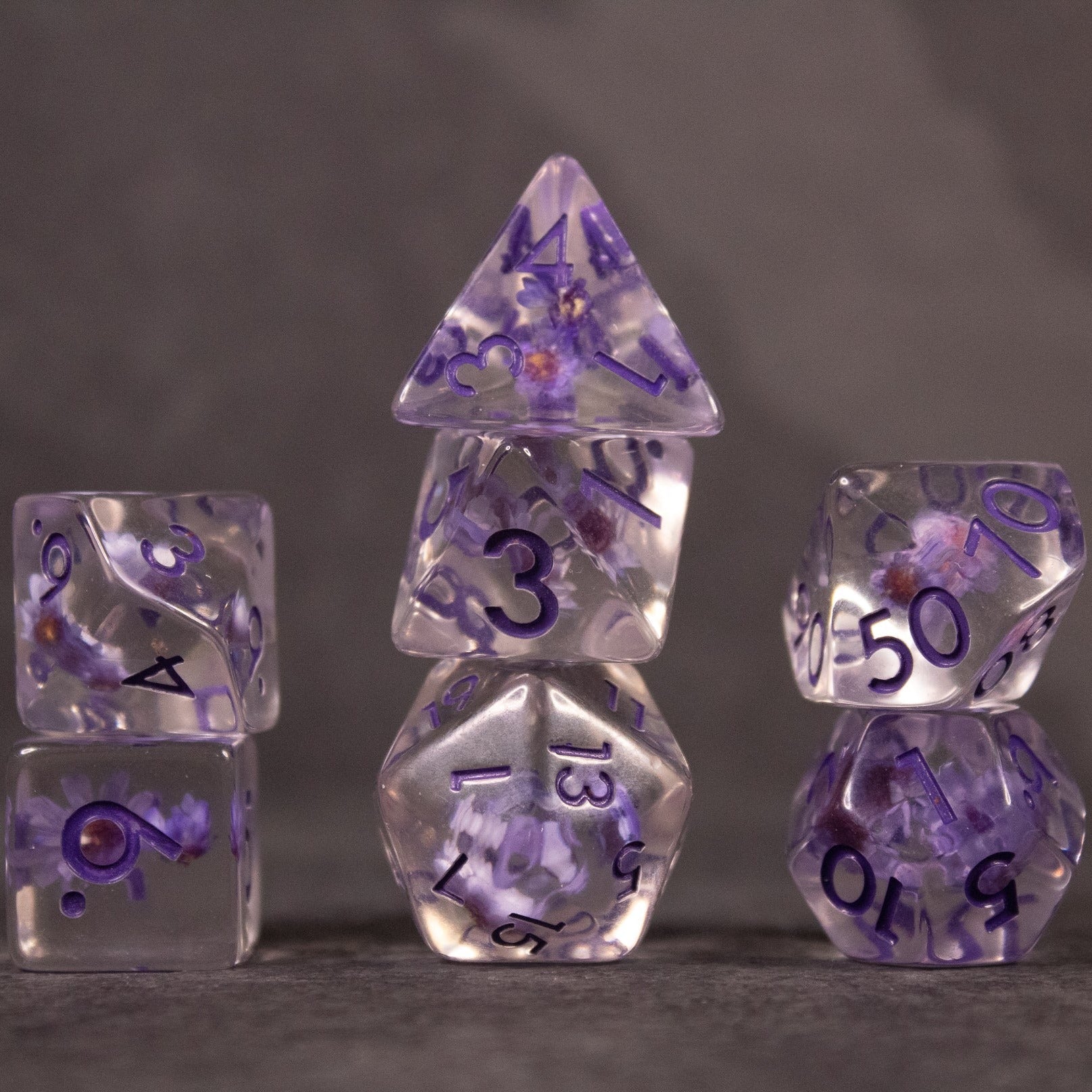 Purple Flower Dice Set - Transparent purple dice set with embedded flower inclusions and black numbering.