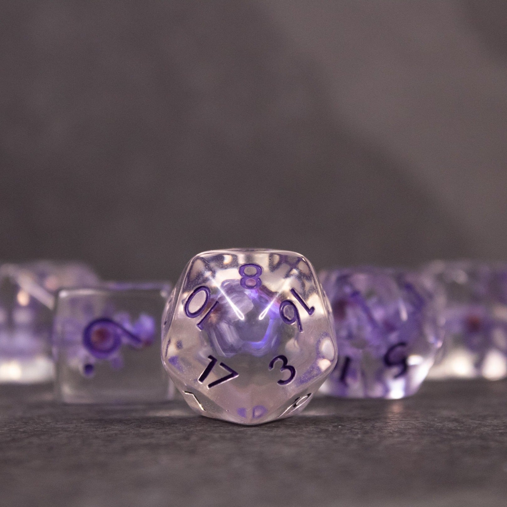 Purple Flower Dice Set - Transparent 20-sided dice with suspended purple flowers inside and black numbering.