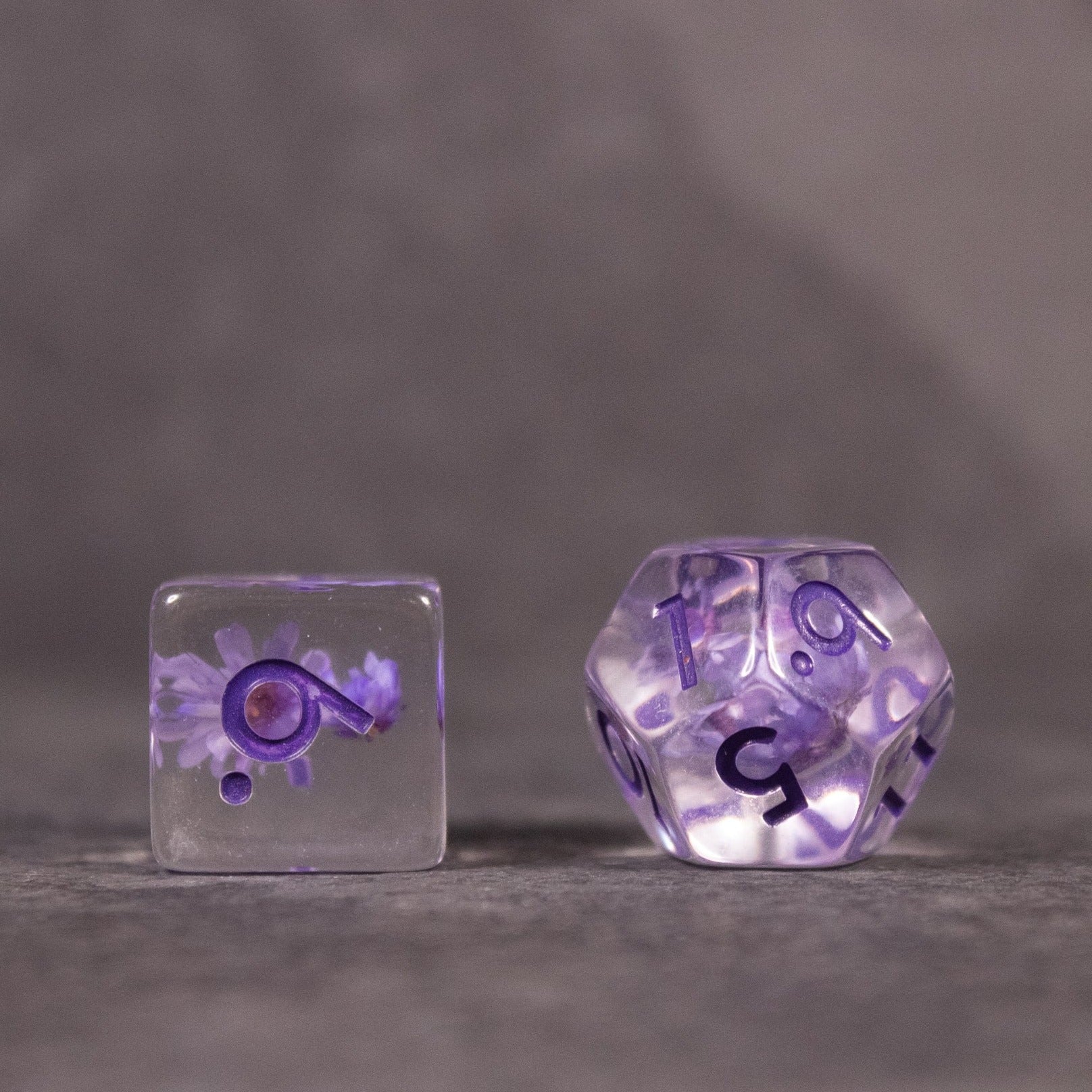 Purple Flower Dice Set - Transparent dice set with purple flower inclusions, featuring a six-sided and a twenty-sided die.
