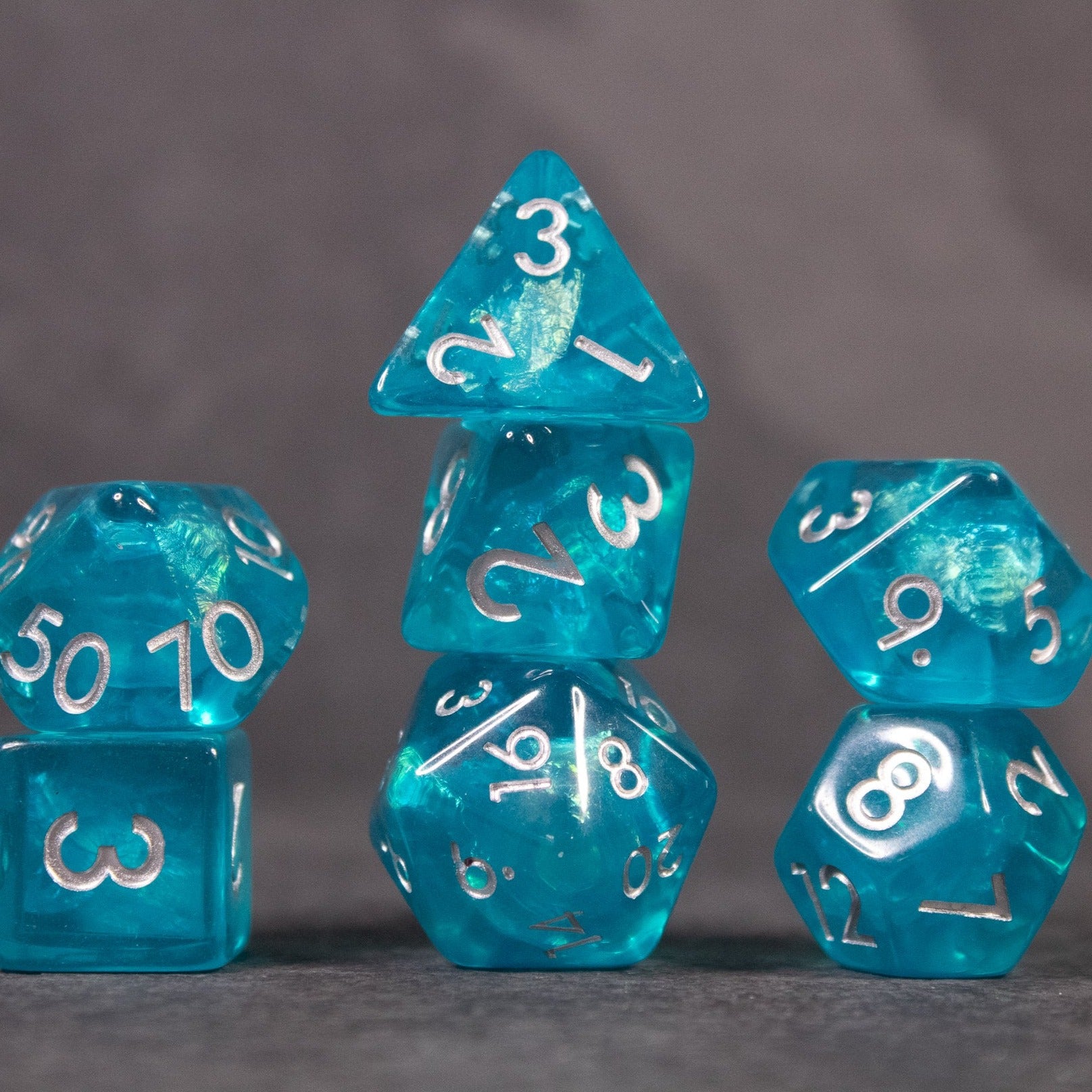 Teal Blue Dice Set - Set of teal blue iridescent dice with white numbers, including d4, d6, d8, d10, d12, and d20.