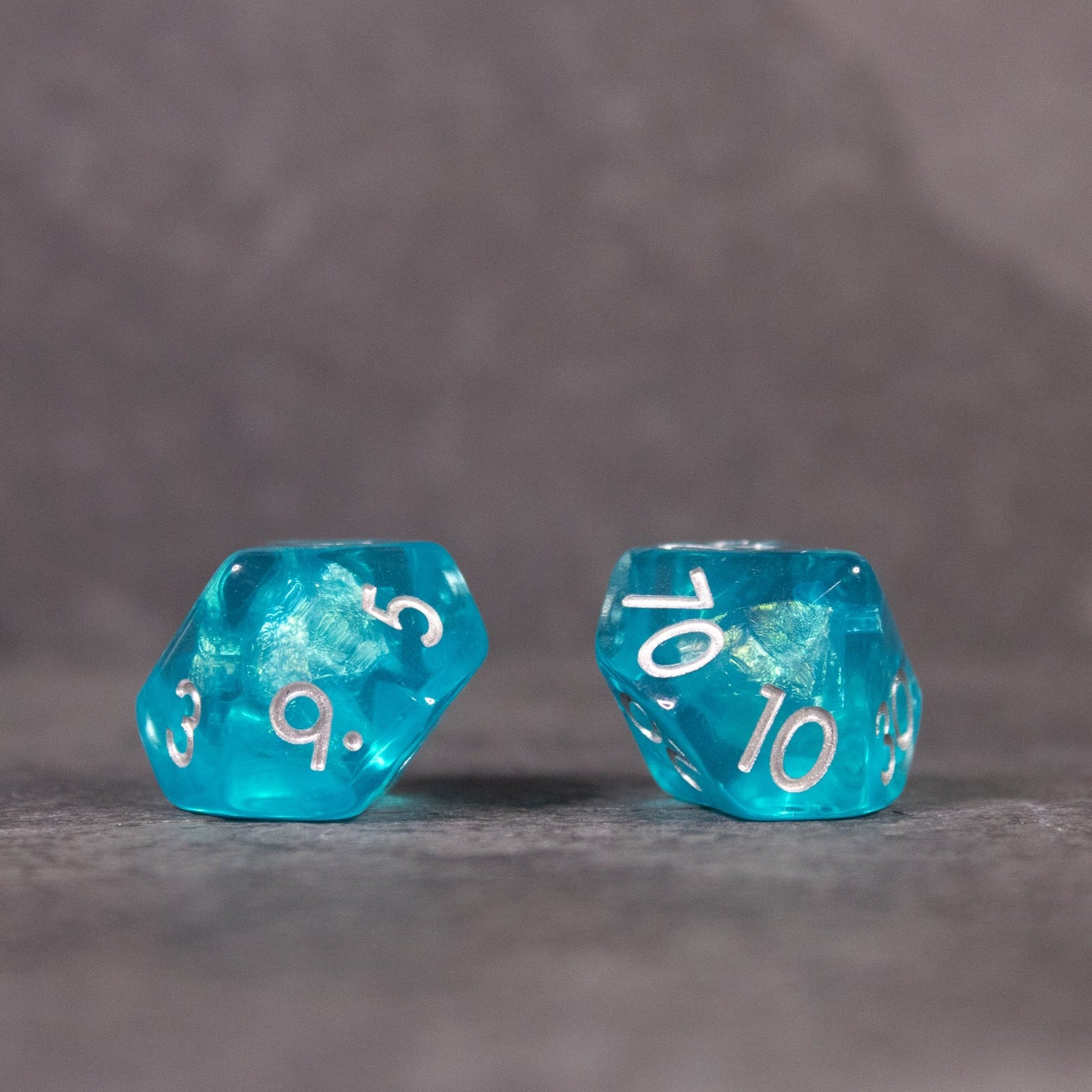 Teal Blue Dice Set - Two translucent teal blue polyhedral dice with white numbering, one showing 9 and the other 10.