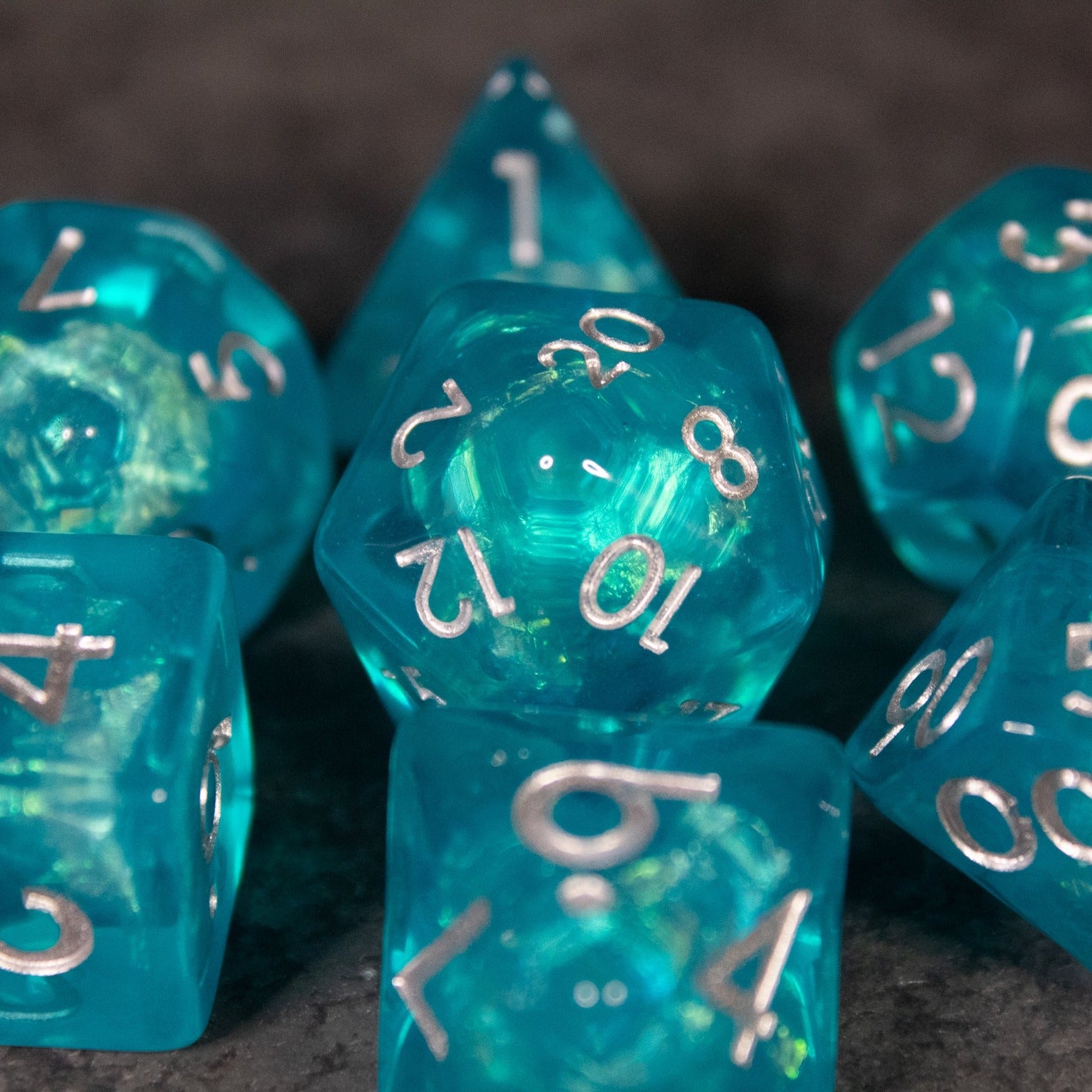 Teal Blue Dice Set - Set of iridescent teal blue polyhedral dice with white numbering and gold flecks inside.