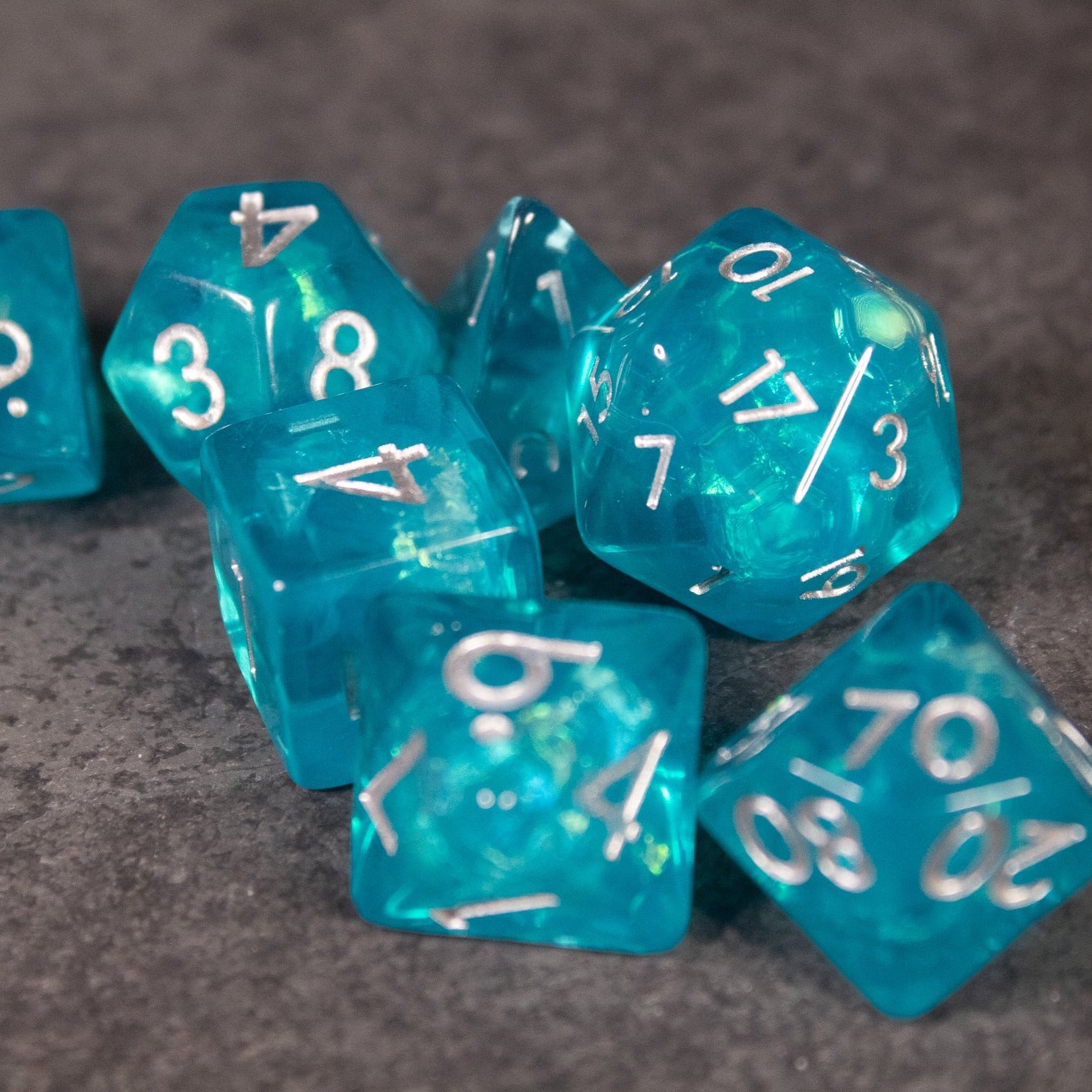 Teal Blue Dice Set - Teal blue iridescent polyhedral dice set with white numbering, including d20, d12, d10, and d8 shapes.