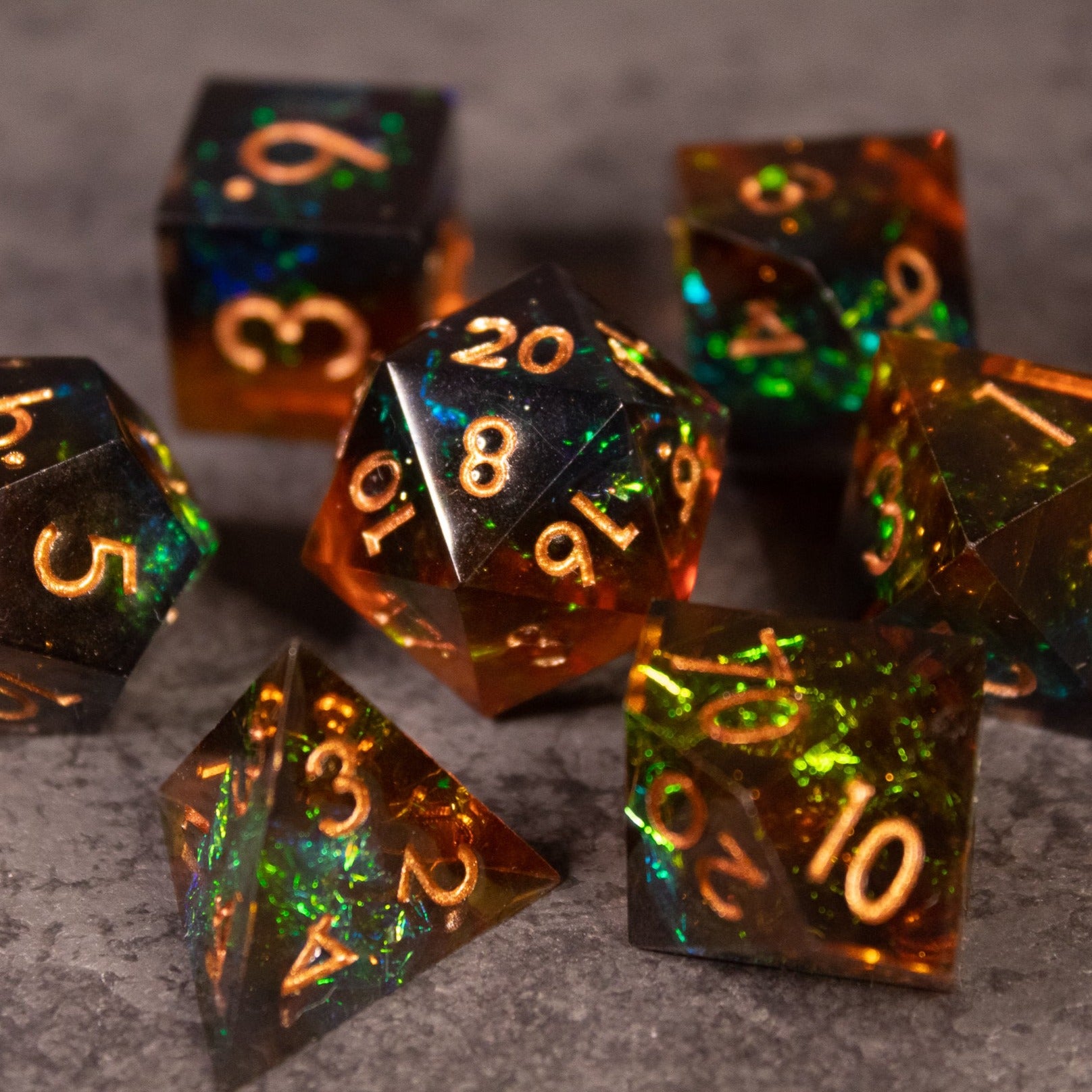 Whiskeyjack Dice Set - Seven sharp-edged polyhedral dice in translucent amber with green and gold flecks and gold numbers.