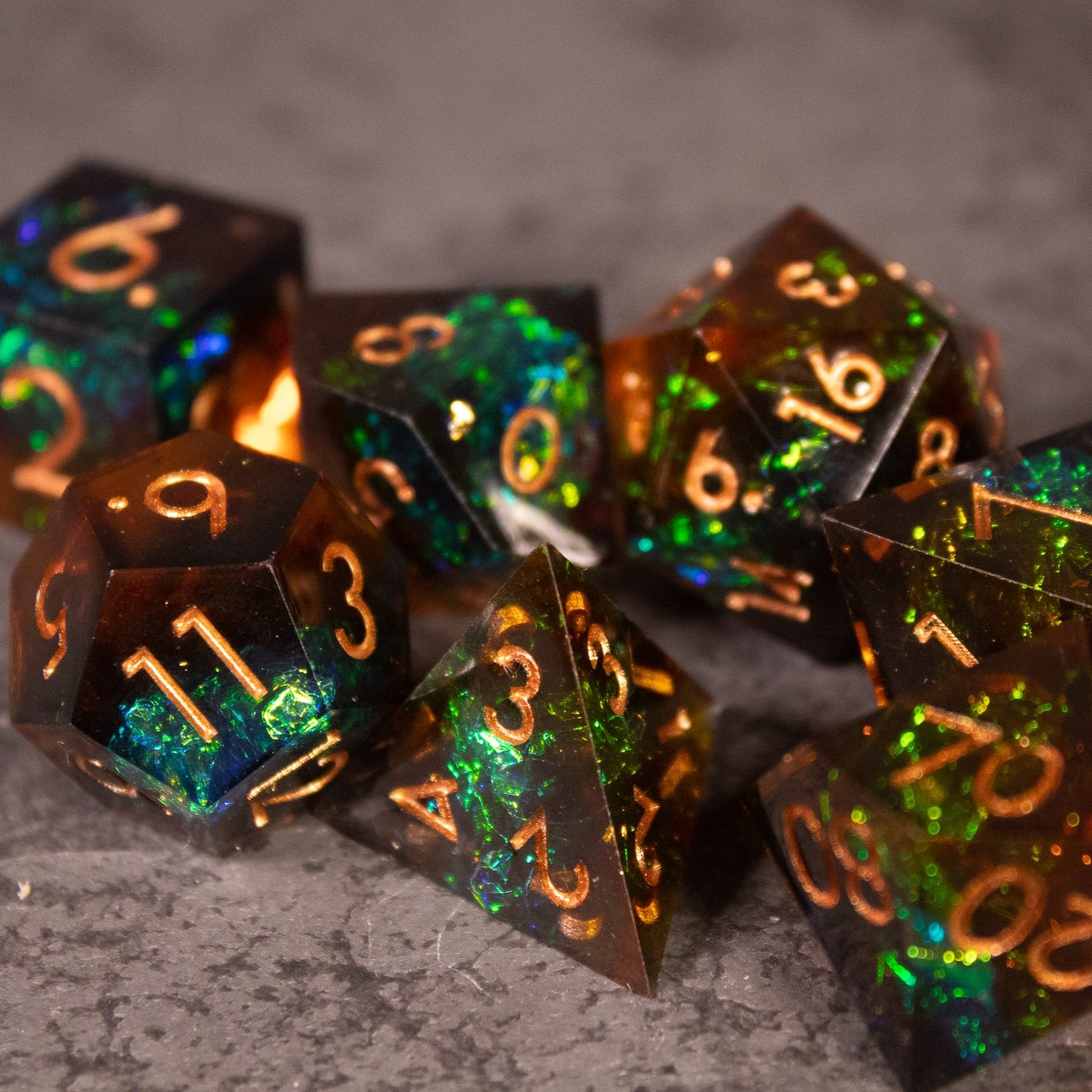 Whiskeyjack Dice Set - Sharp-edged polyhedral dice set with translucent dark green and amber colors and gold numbers.