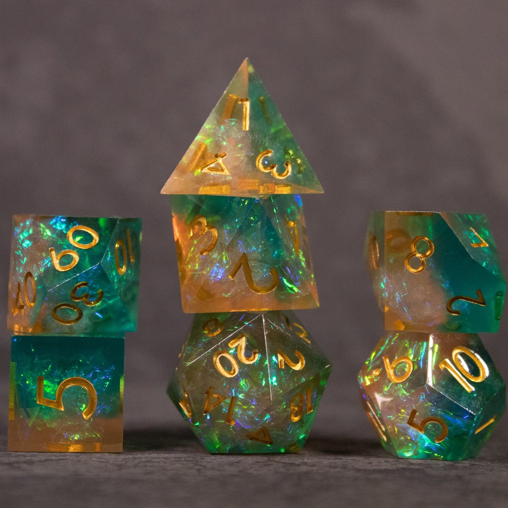 Seafarer Dice Set - Green and orange translucent sharp-edged dice set with gold numbering on gray background.