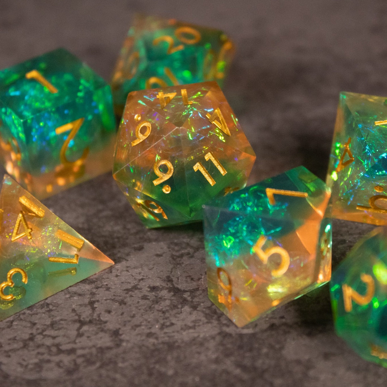Seafarer Dice Set - Green and orange sharp-edged polyhedral dice with gold numbering on a textured surface.