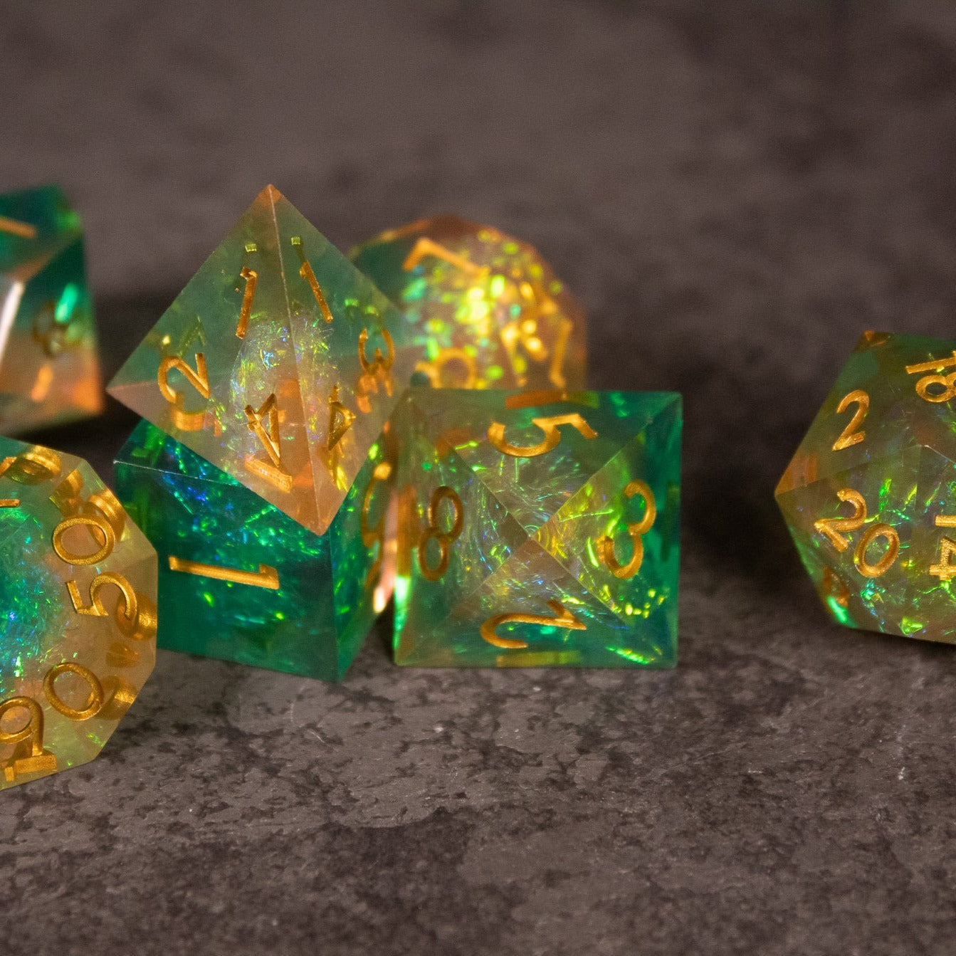 Seafarer Dice Set - Set of translucent green and orange sharp-edged polyhedral dice with gold numbering on a dark surface.