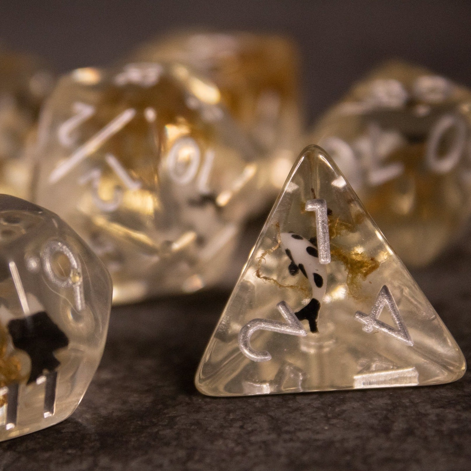 Koi Pond Dice Set - Translucent beige tetrahedron dice with black koi fish inclusions and white numbers.
