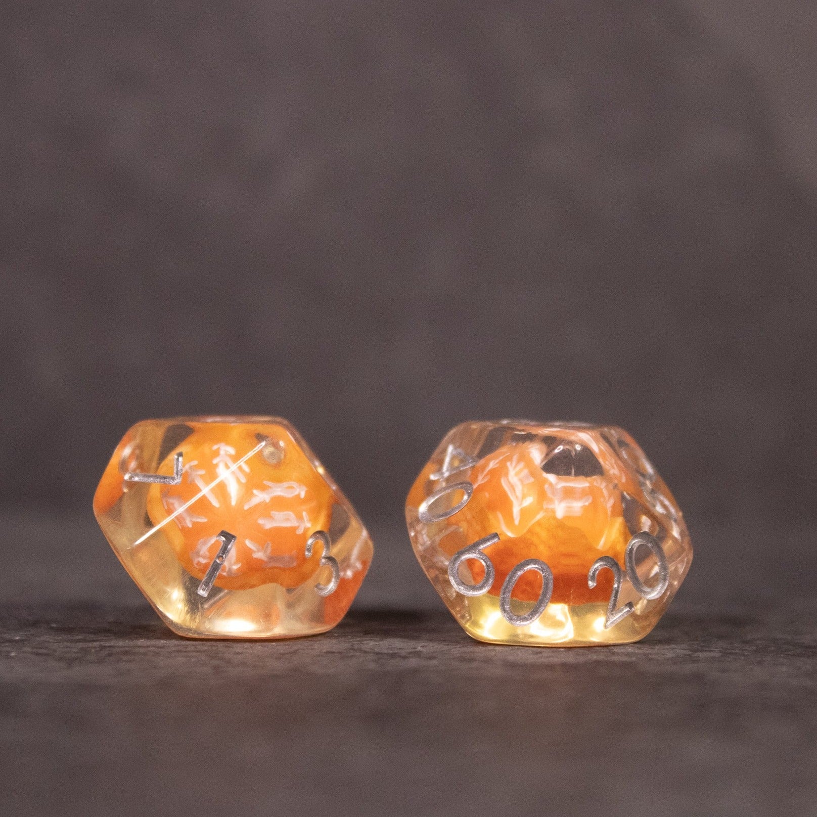 Orange Fruit Dice Set - Two translucent dice with embedded orange fruit slices and white numbering on a dark surface.