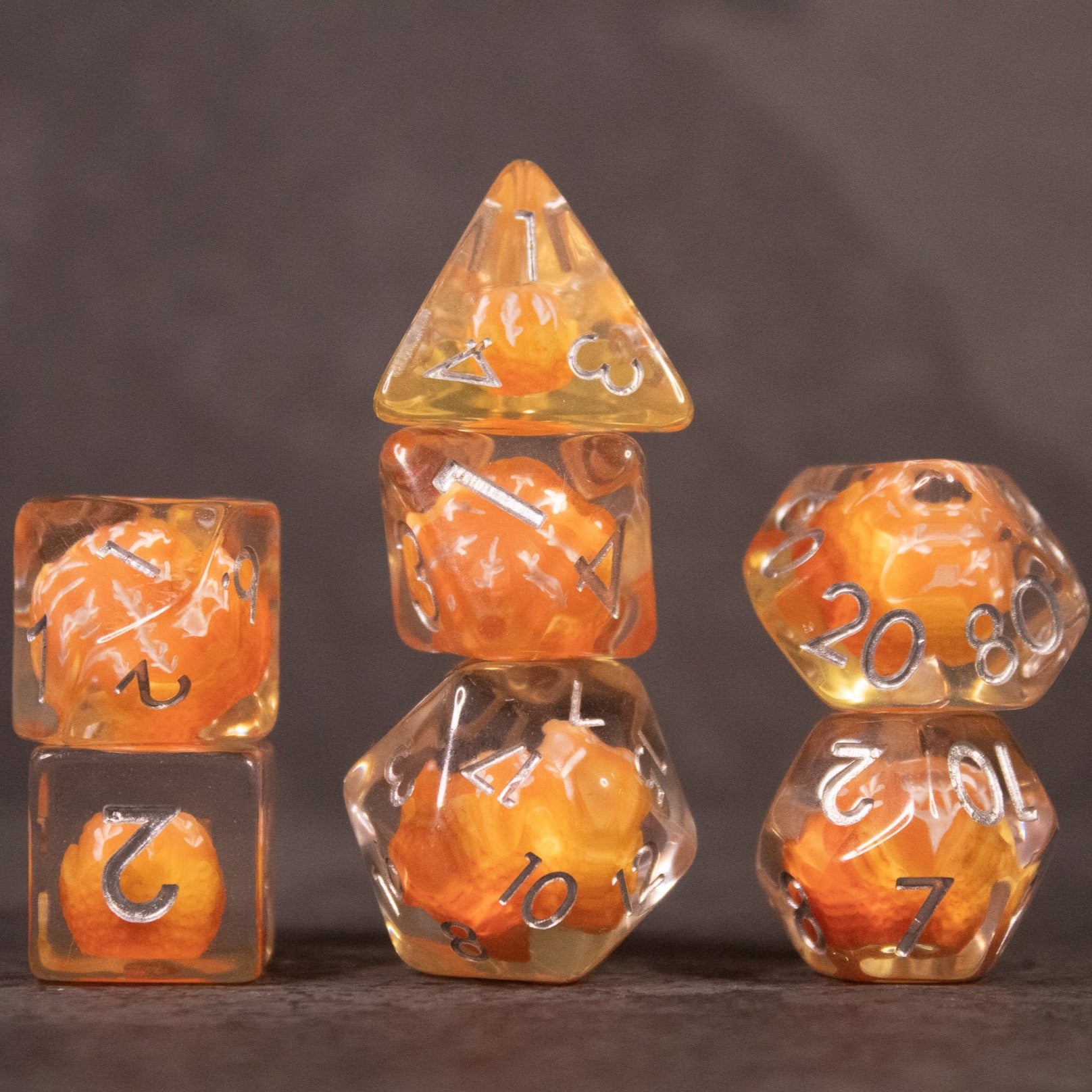 Orange Fruit Dice Set - Set of seven transparent dice with orange fruit pieces inside, black numbering visible on each die.