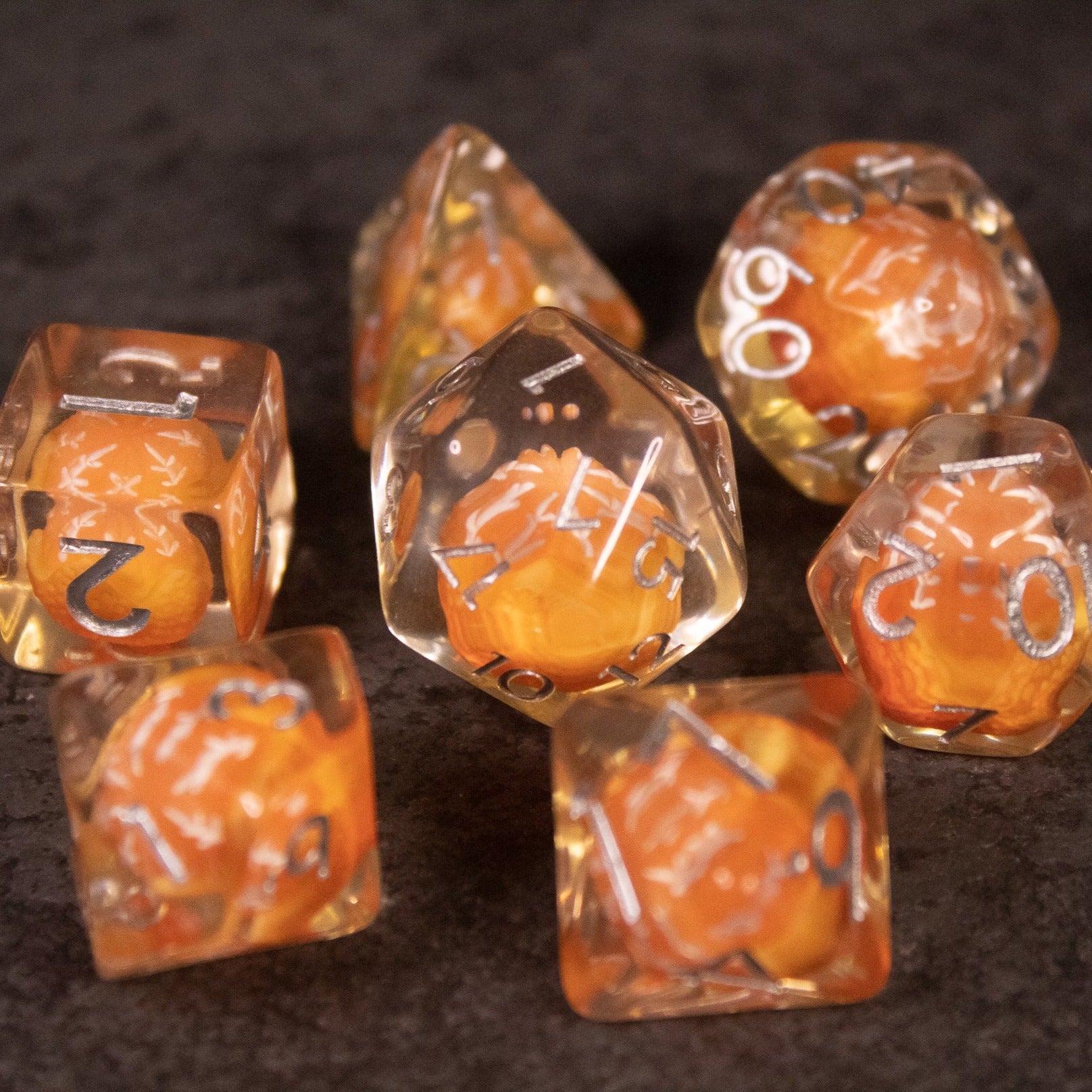 Orange Fruit Dice Set - Set of transparent polyhedral dice with miniature orange fruit inside and white numbering.