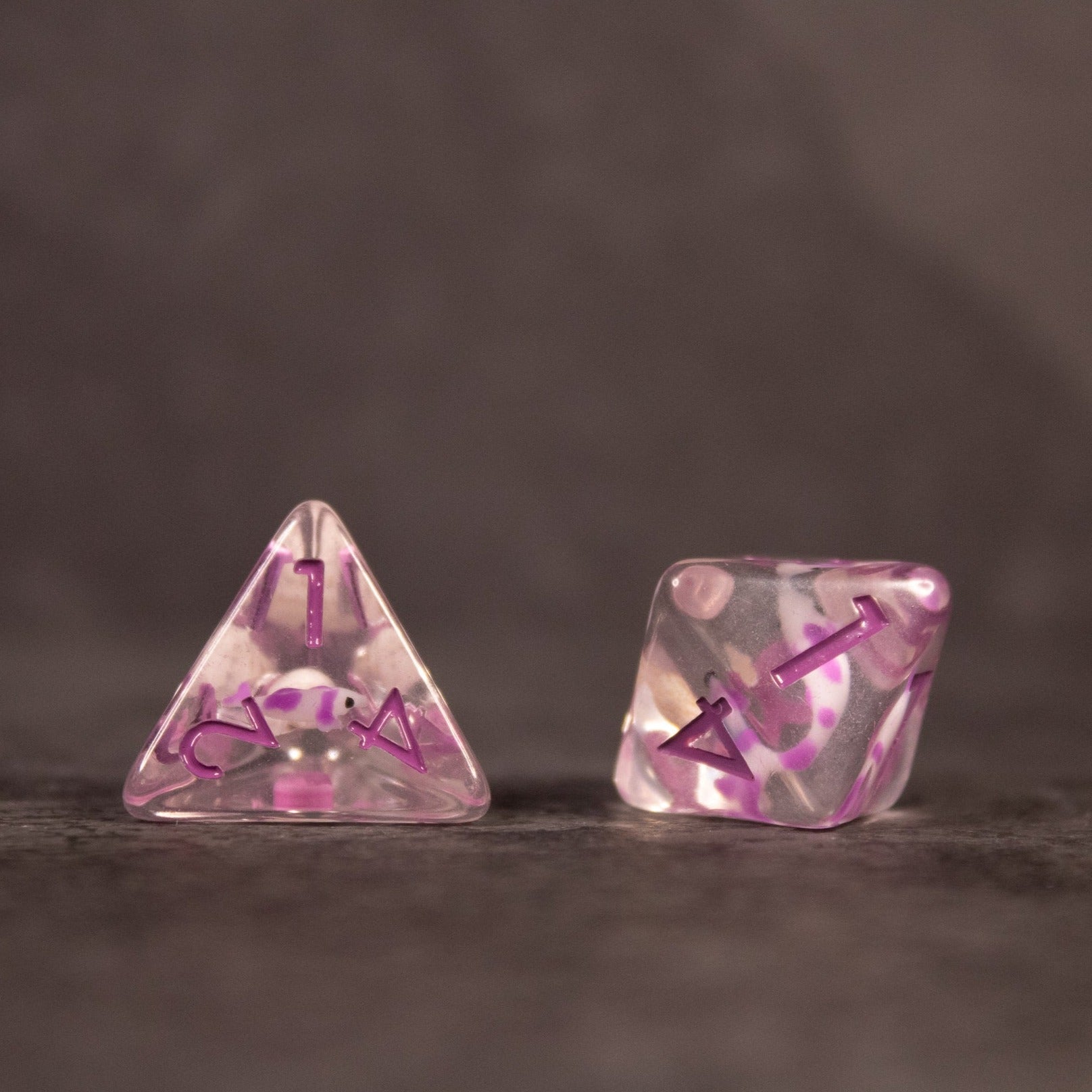 Purple Koi Fish and Seashell Dice Set - Translucent purple four-sided and six-sided dice with koi fish and seashell designs and purple numbering.